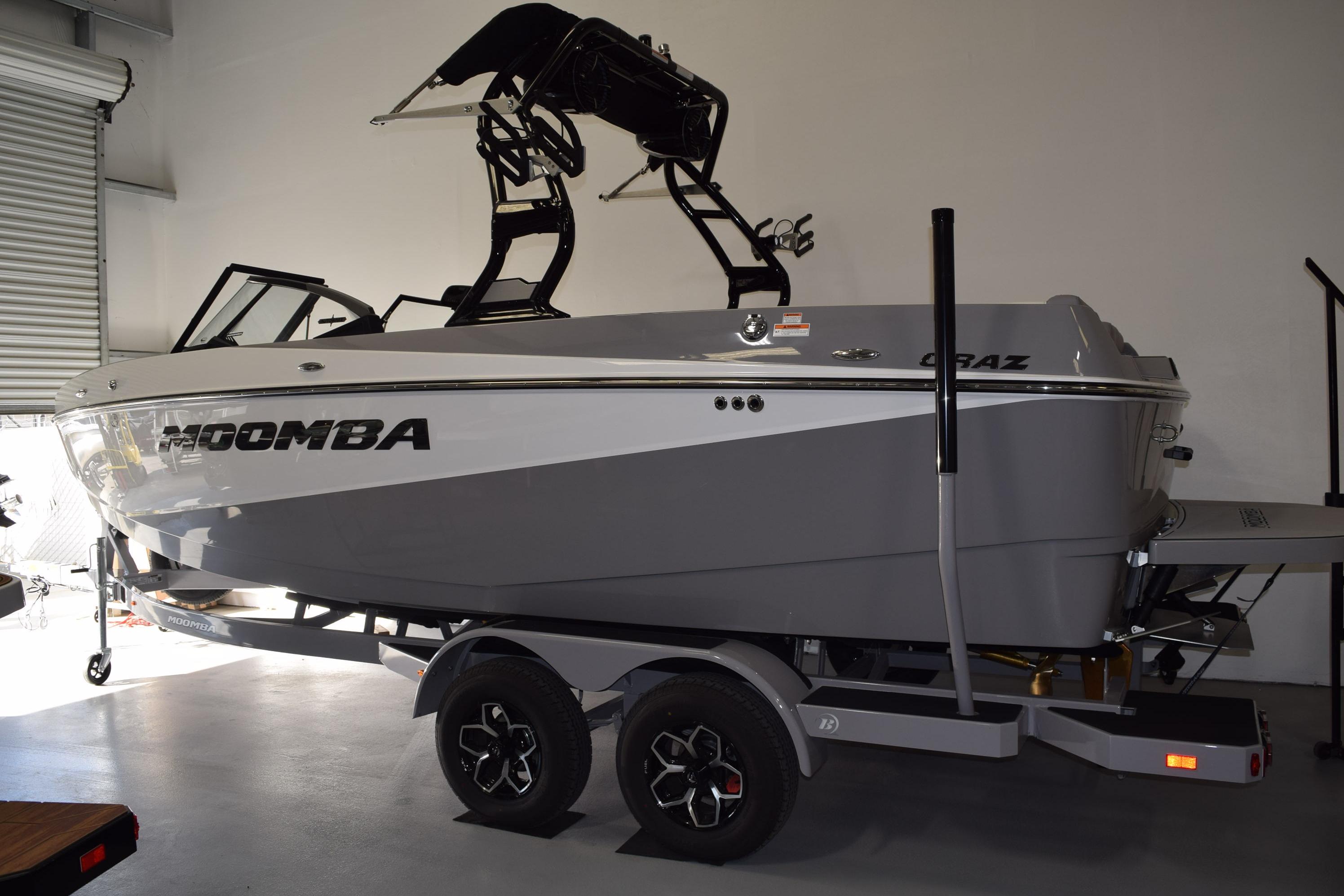 2026 Moomba Craz boat in showroom, gray and white design, on trailer.