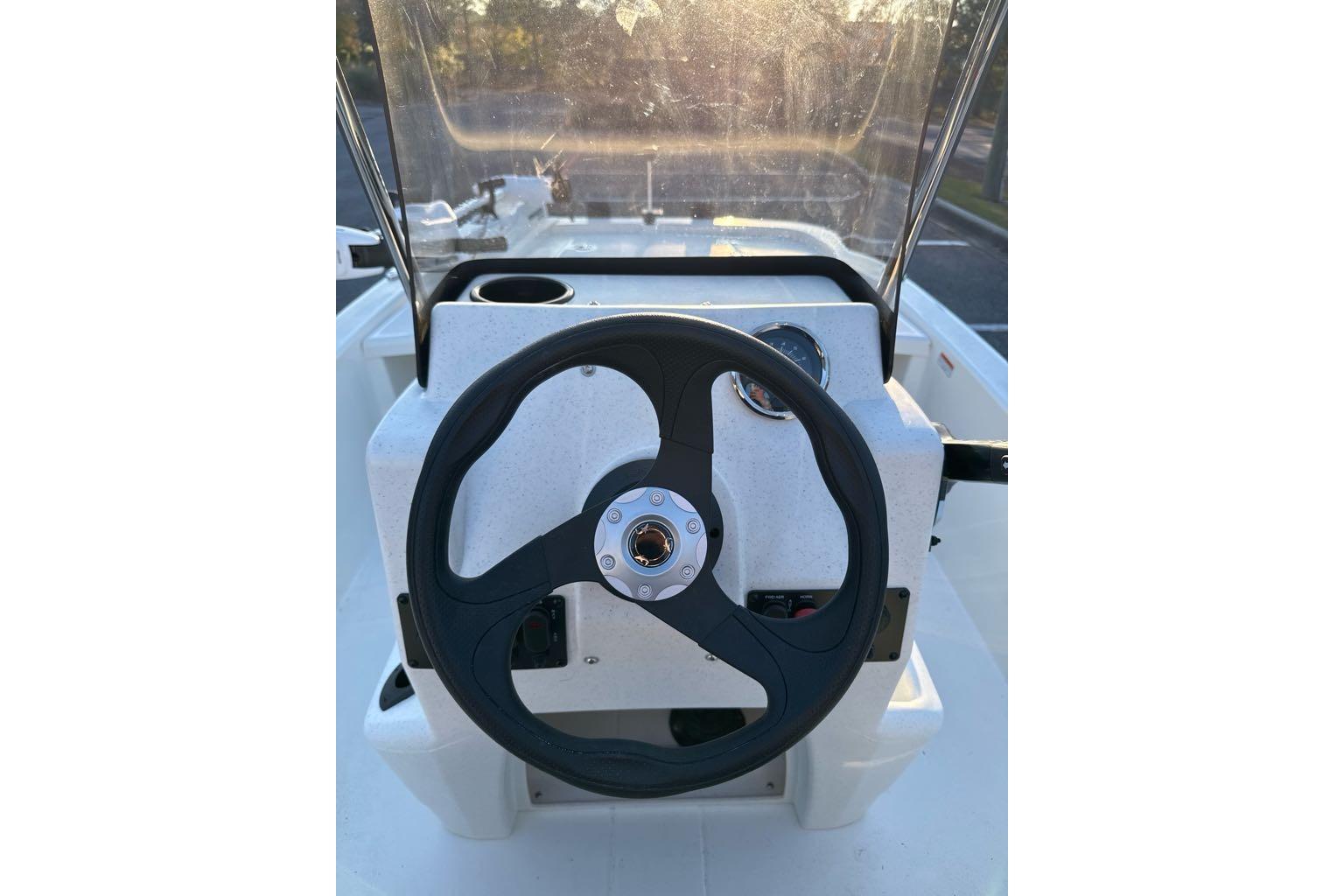 2026 Mako Pro Skiff 13 CC steering console with black wheel and clear windshield.