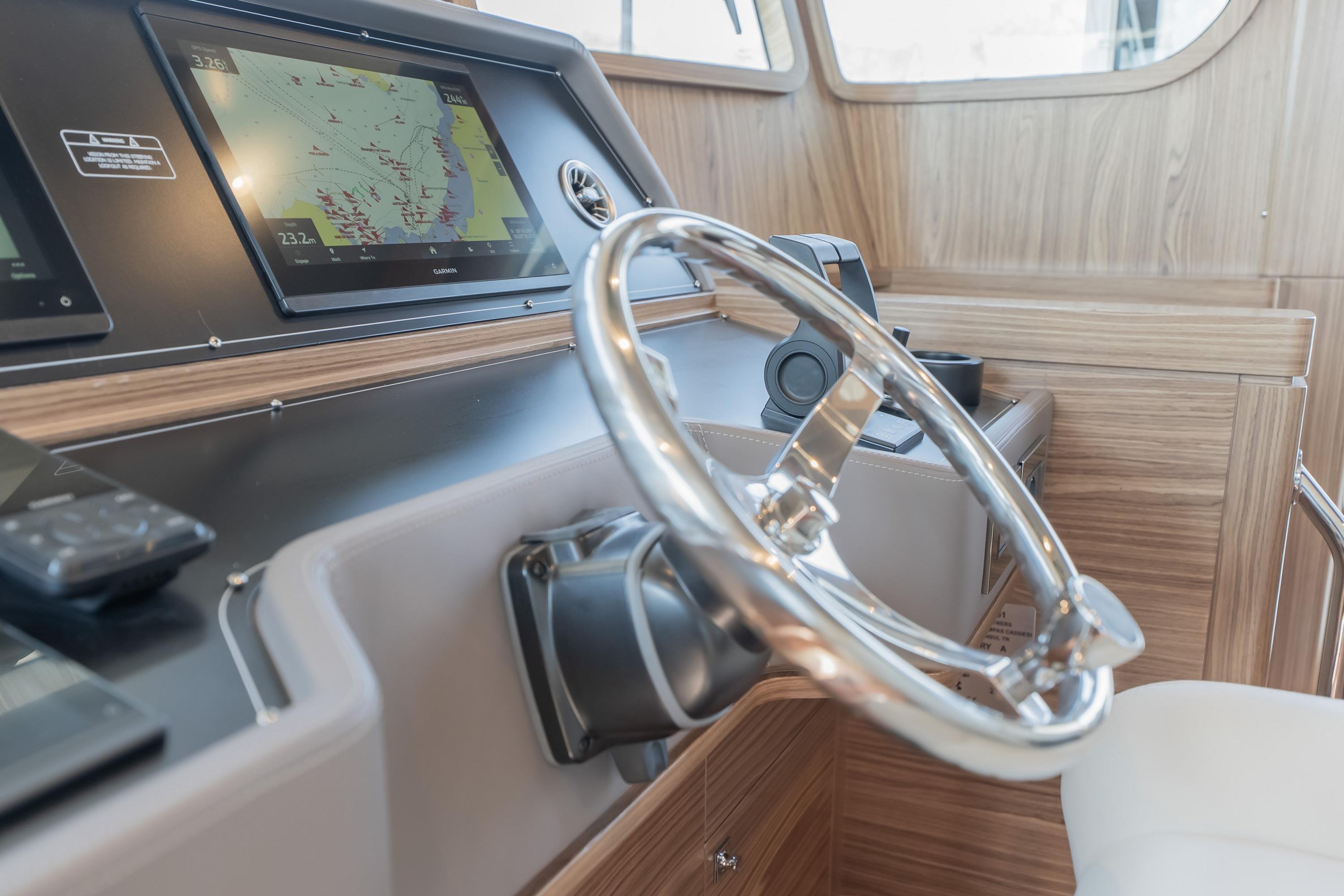 2024 Nordhavn 51 yacht helm with navigation screens and polished steering wheel.