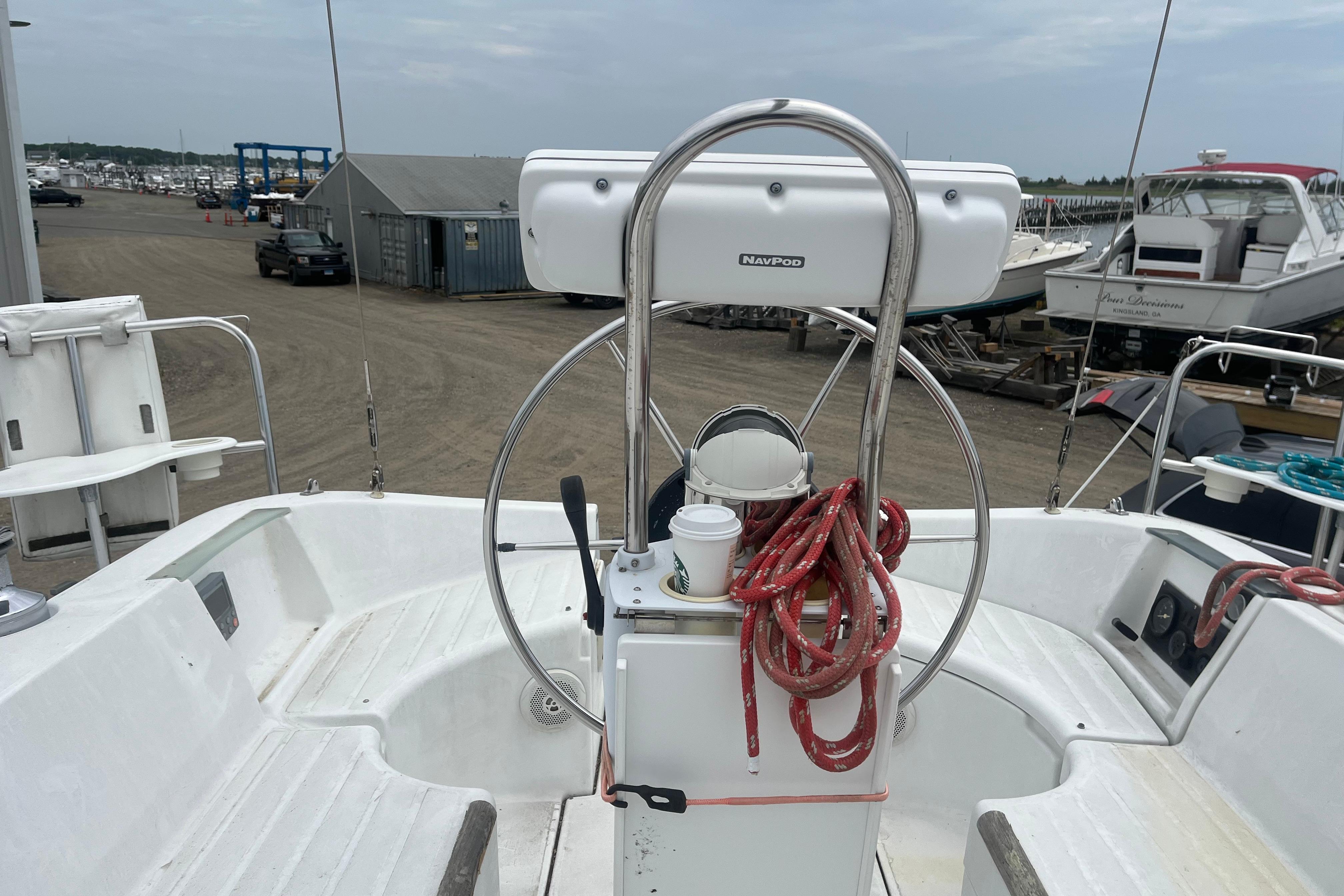 Cockpit of 1999 Benneteau 321 Oceanis sailboat with steering wheel and red ropes.