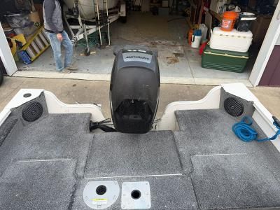 A boat with gray carpeting and an outboard motor in a garage.