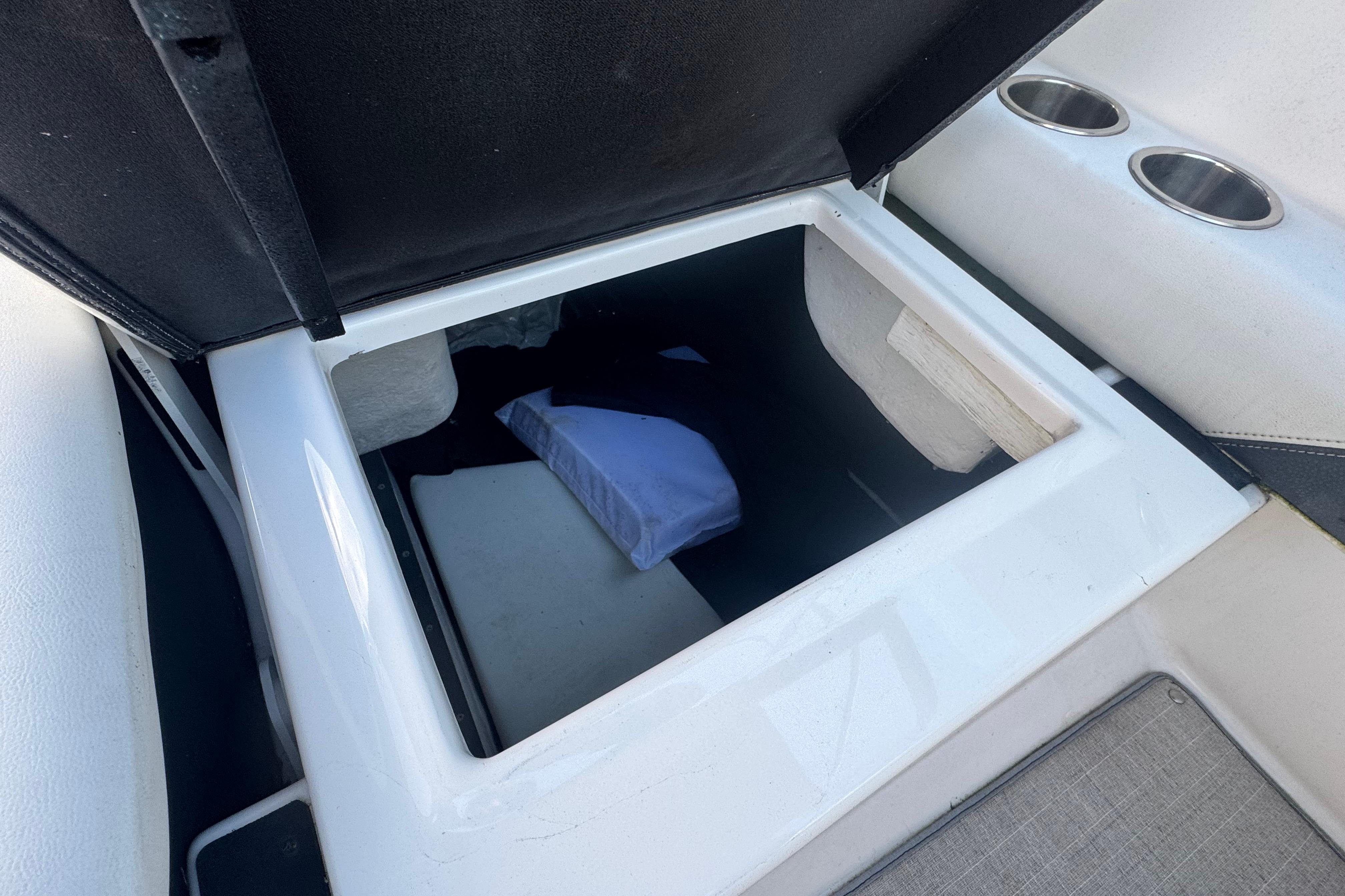 Open storage compartment on 2017 Regal 23 OBX boat with cup holders.
