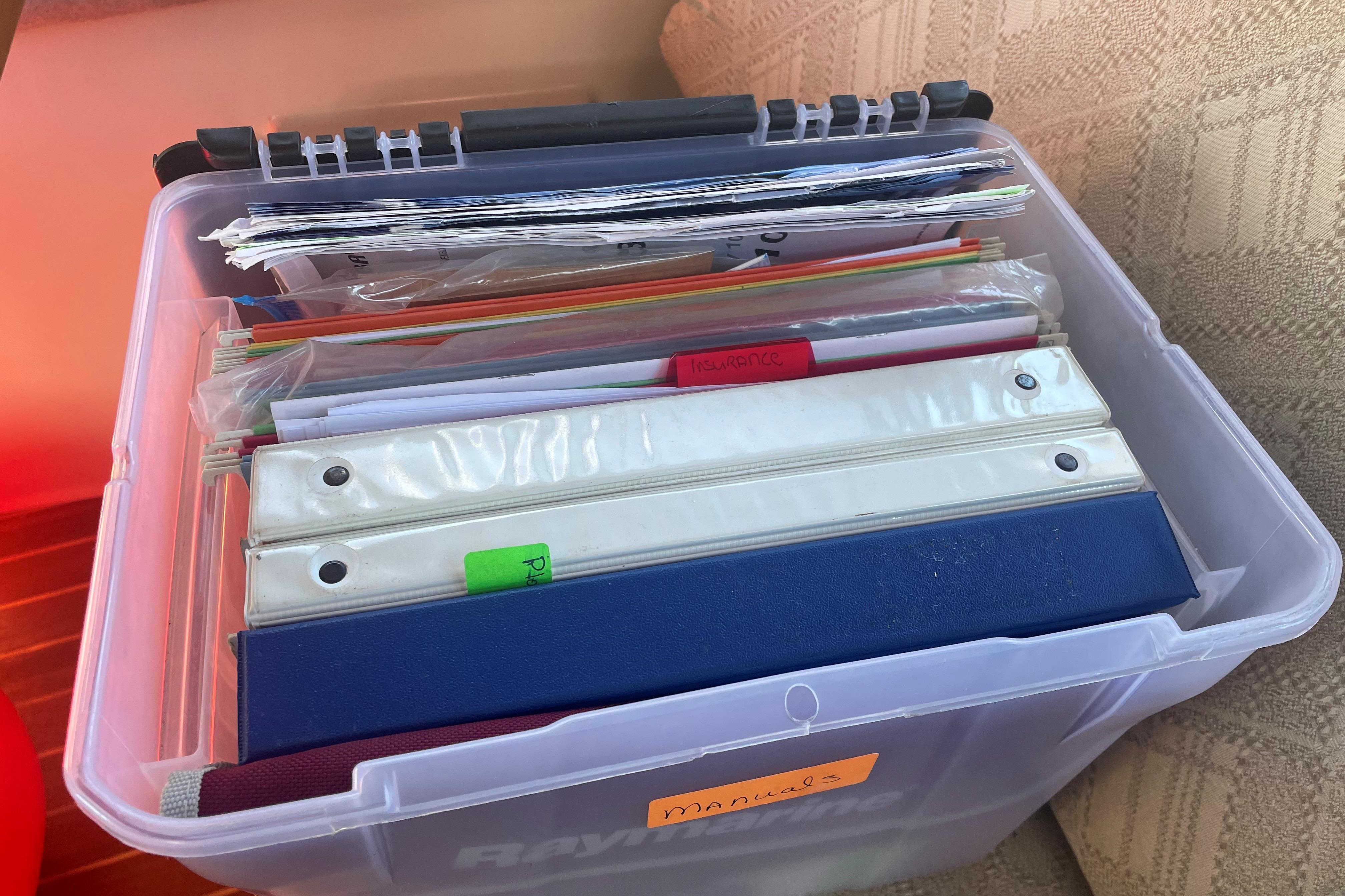 Plastic storage box with organized manuals and binders for a 2007 Ranger Tugs R-25 boat.
