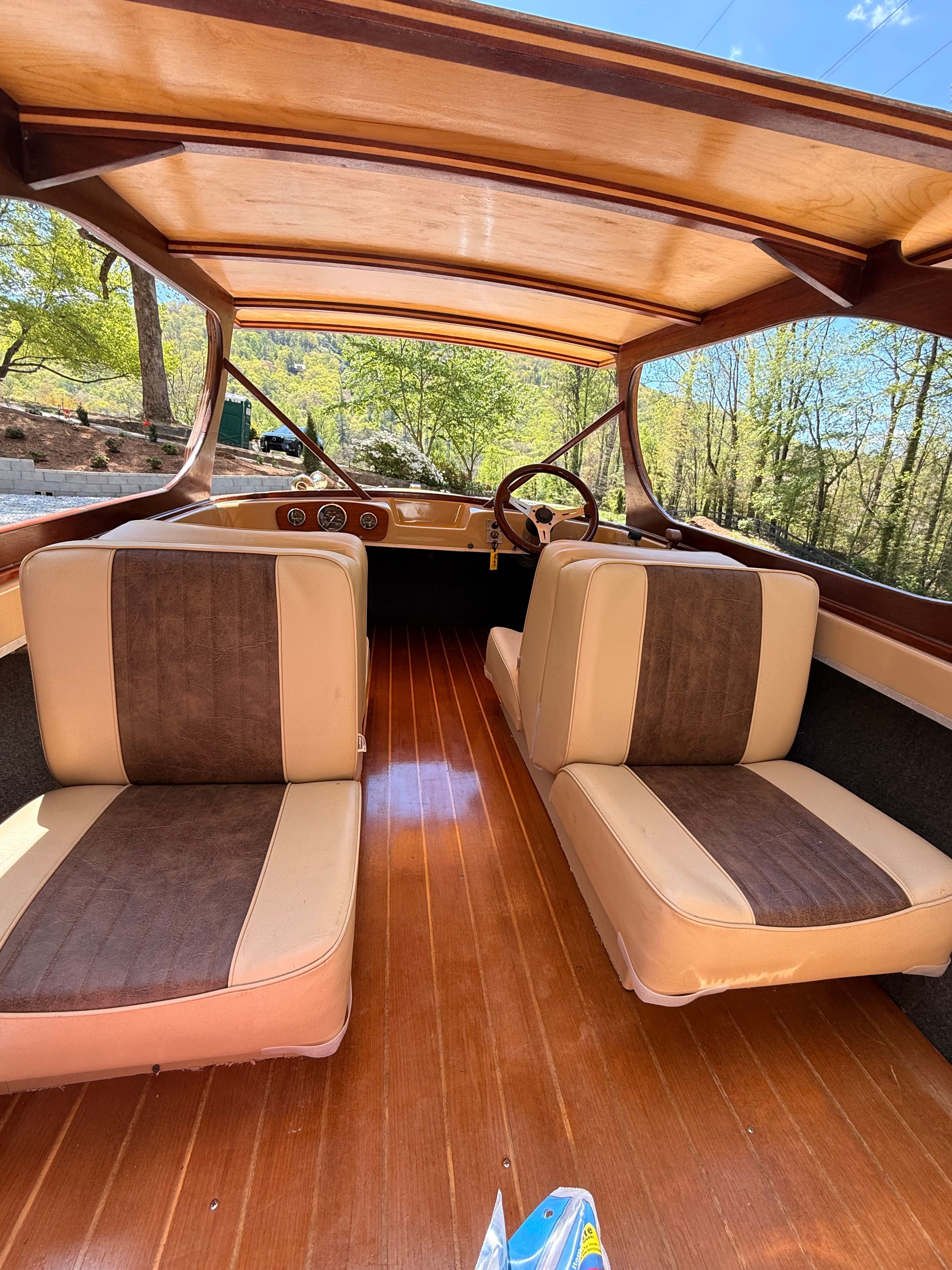 Interior of a vintage boat with wooden flooring and cushioned seats.