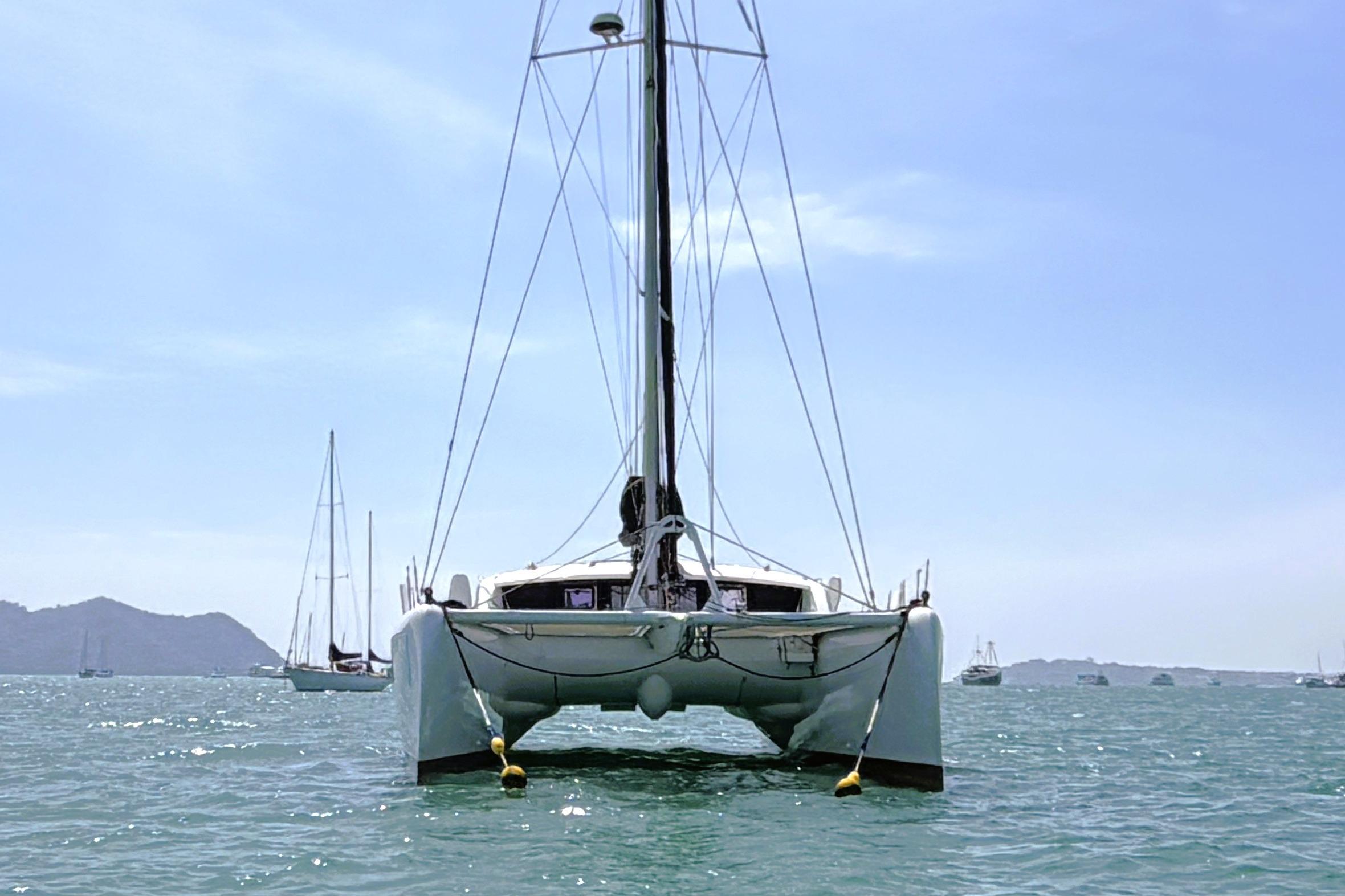 2017 Outremer 51 catamaran sailing on a sunny day with distant sailboats.