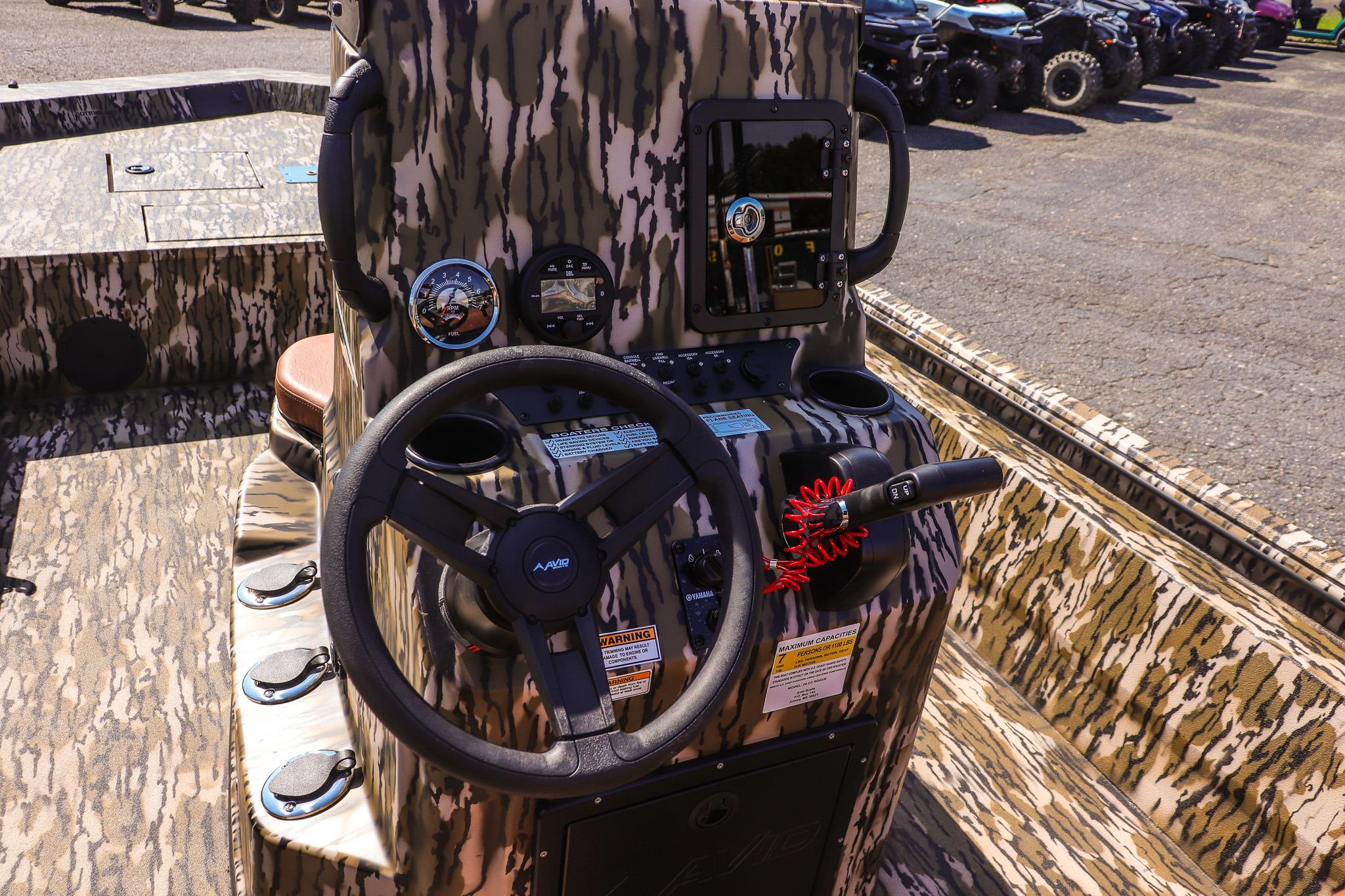 The image shows the cockpit of an Avid 20 Rogue CC boat with a camouflage design.