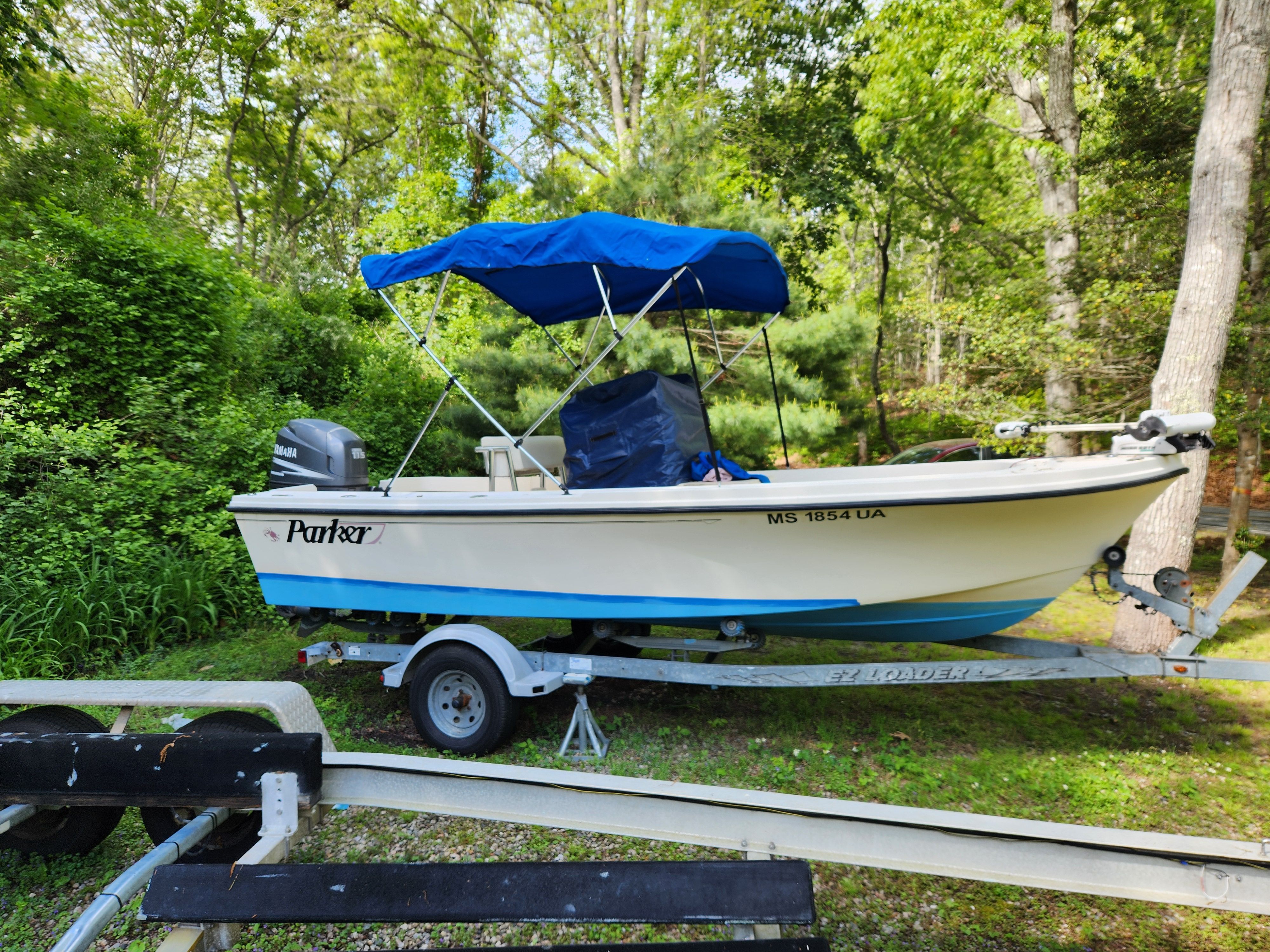 A 2004 Parker 1801 Center Console boat on a trailer surrounded by greenery.