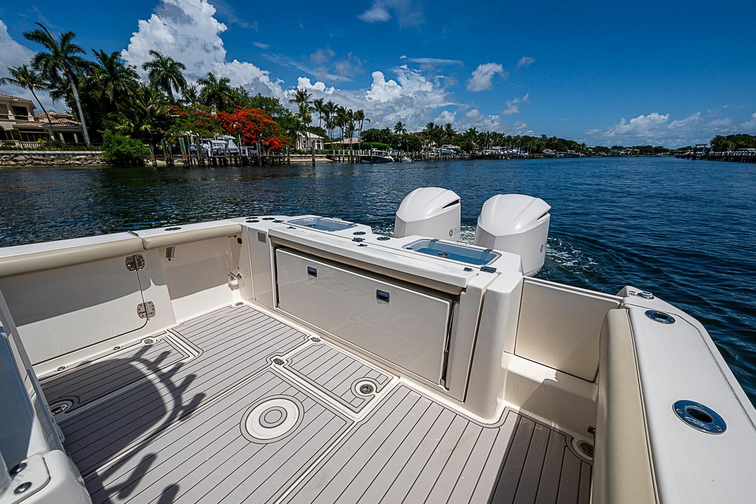 2019 Cobia 320 Center Console boat on calm water, featuring spacious deck and twin engines.