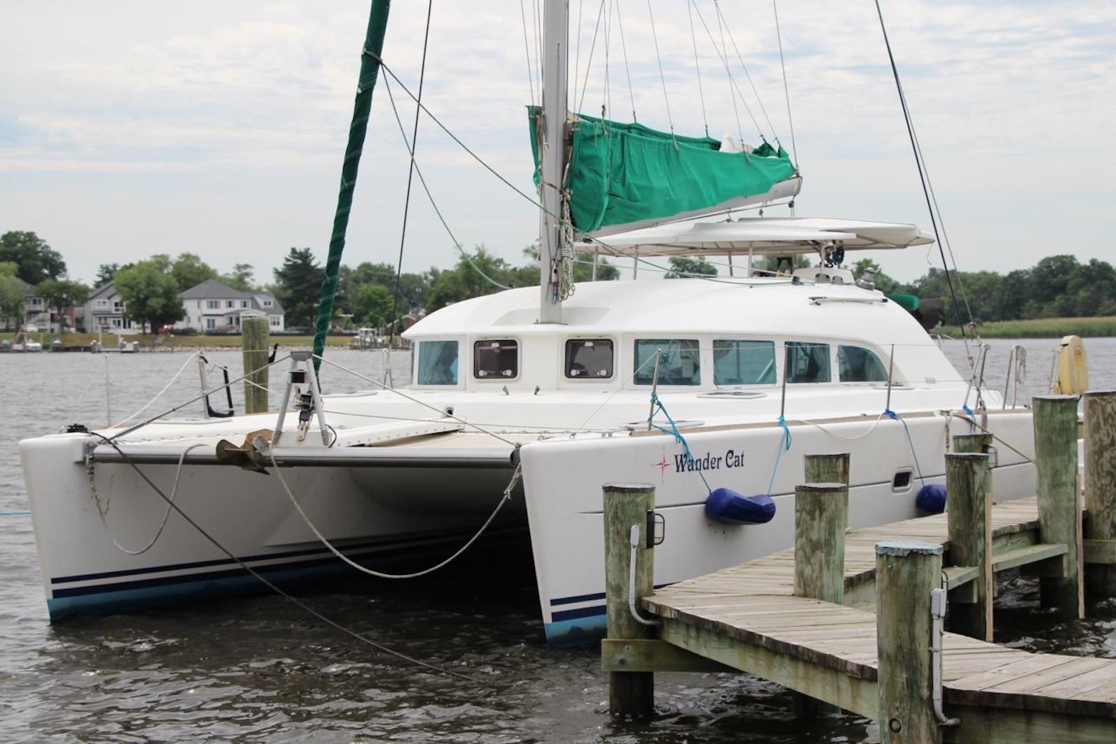 2004 Lagoon 380 catamaran docked at a marina with green sail cover.