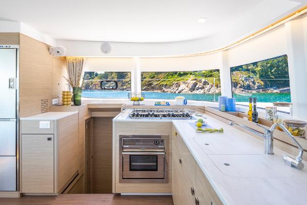 Modern kitchen interior of 2025 Lagoon 43 yacht with scenic ocean view.