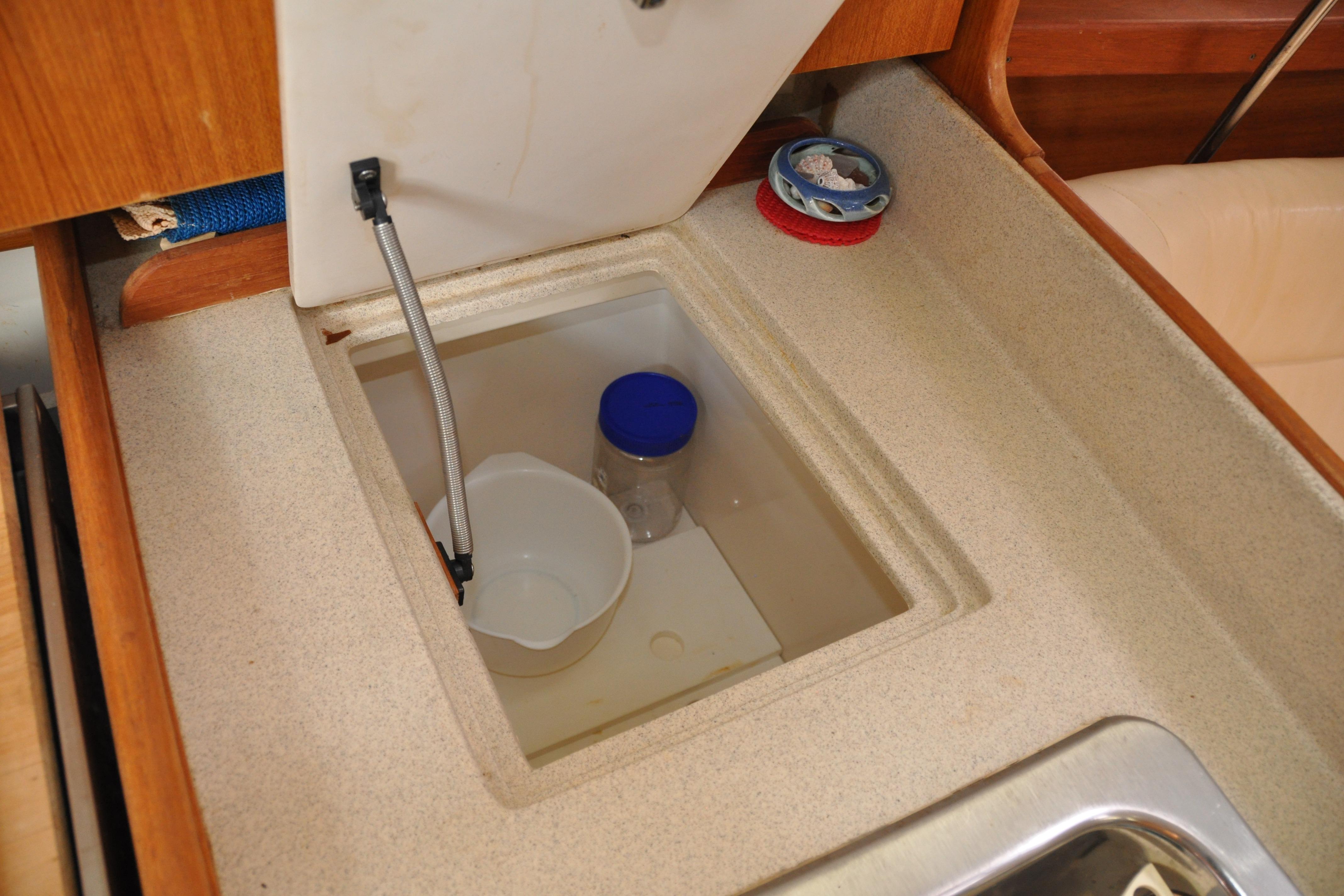 Storage compartment in a 2003 Catalina 387 yacht kitchen with containers and a faucet.