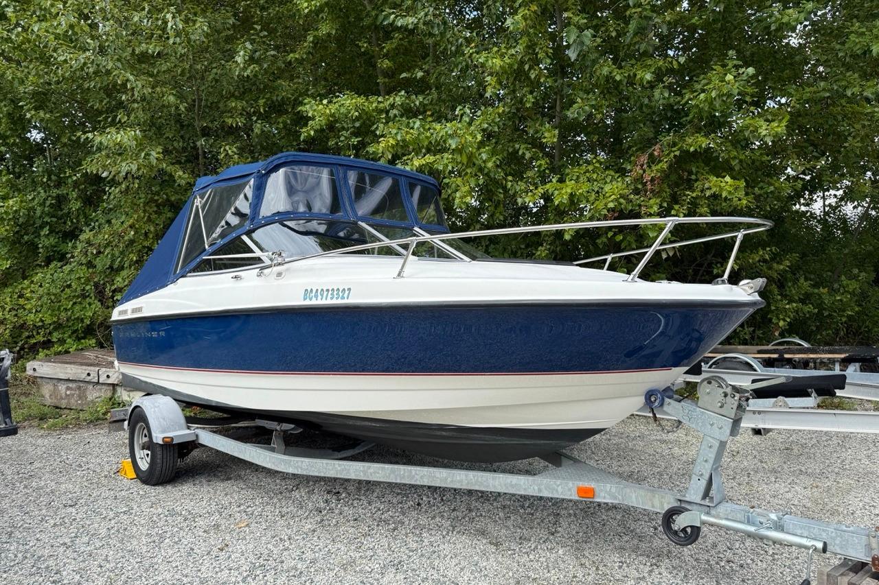2005 Bayliner 210 Discovery boat on trailer, surrounded by trees.