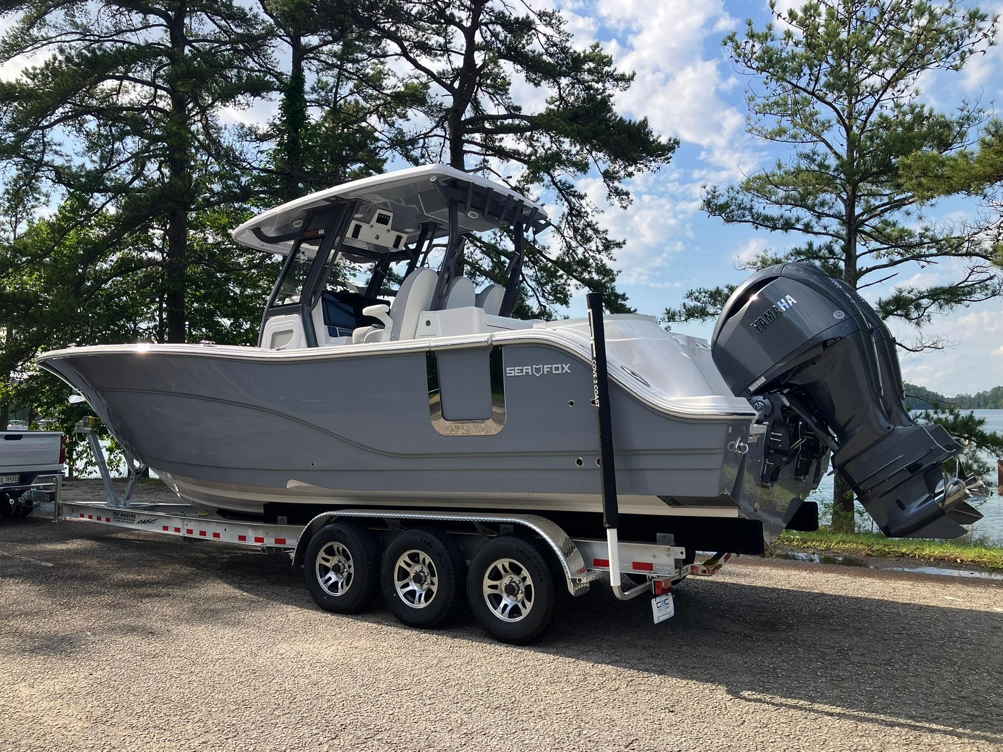 2025 Sea Fox 328 Commander boat on trailer, parked near a lake with trees.