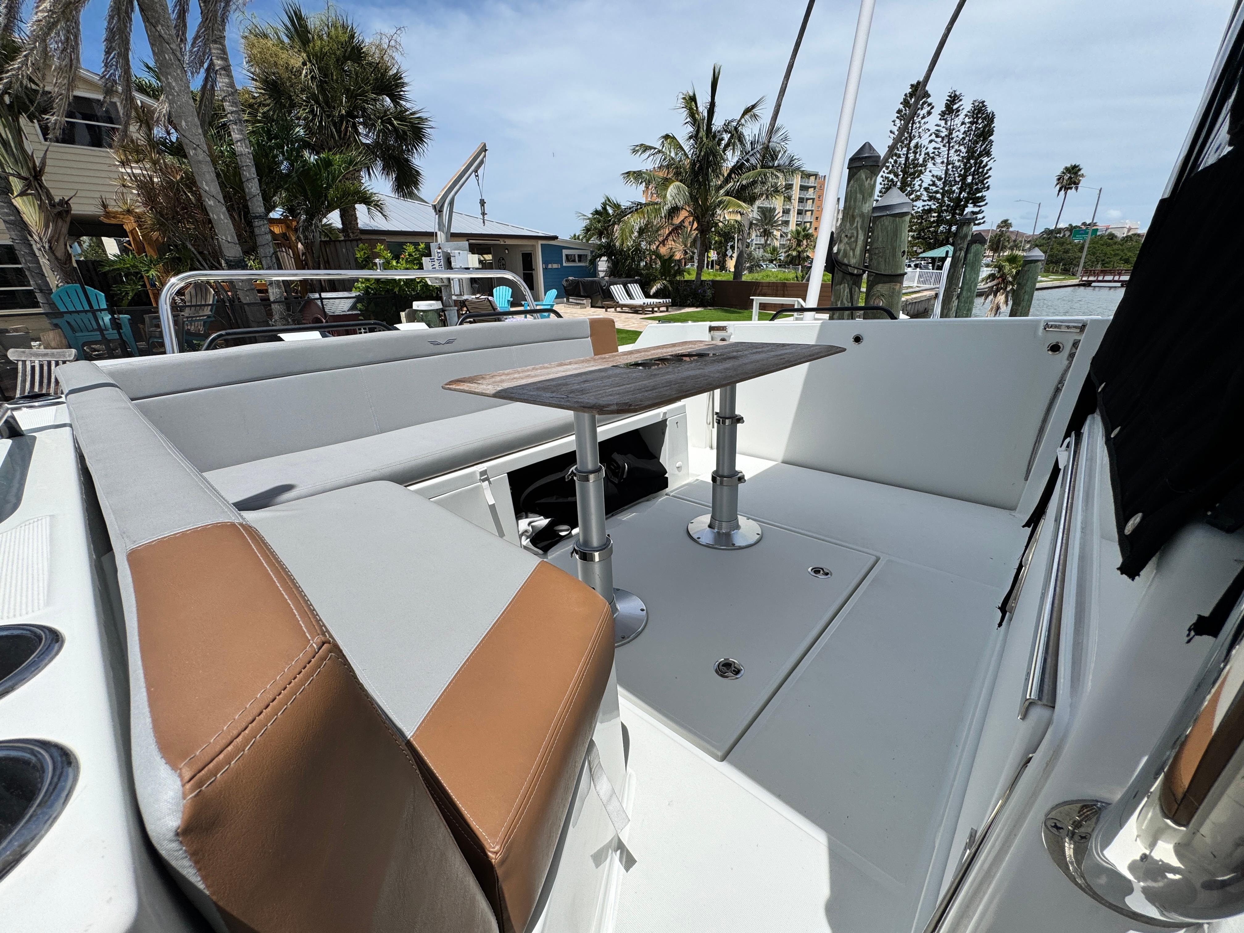 2022 Beneteau Flyer 9 SUNdeck boat interior with seating and table, docked near palm trees.