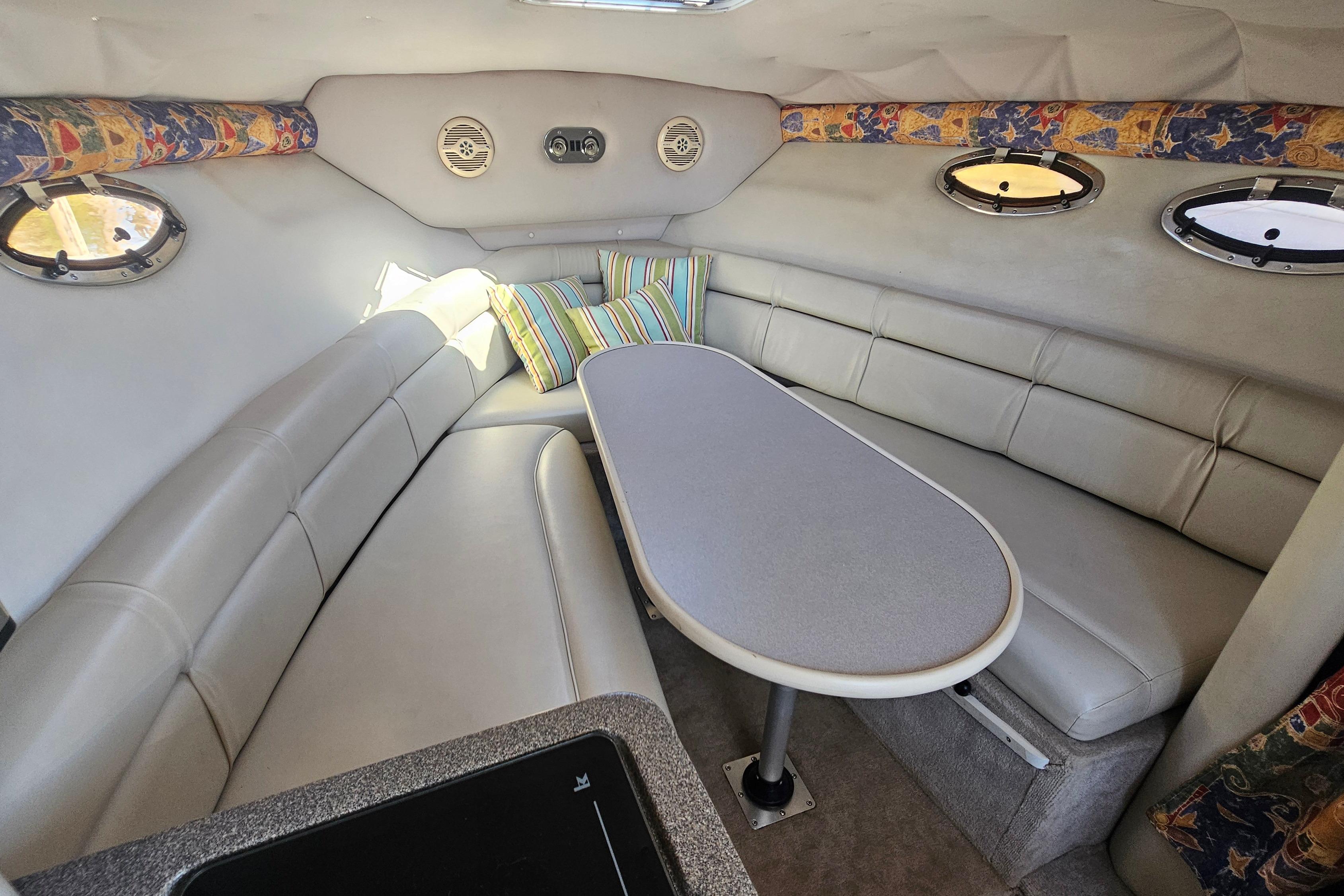 Interior of 2000 Crownline 242 CR boat with cozy seating and colorful pillows.