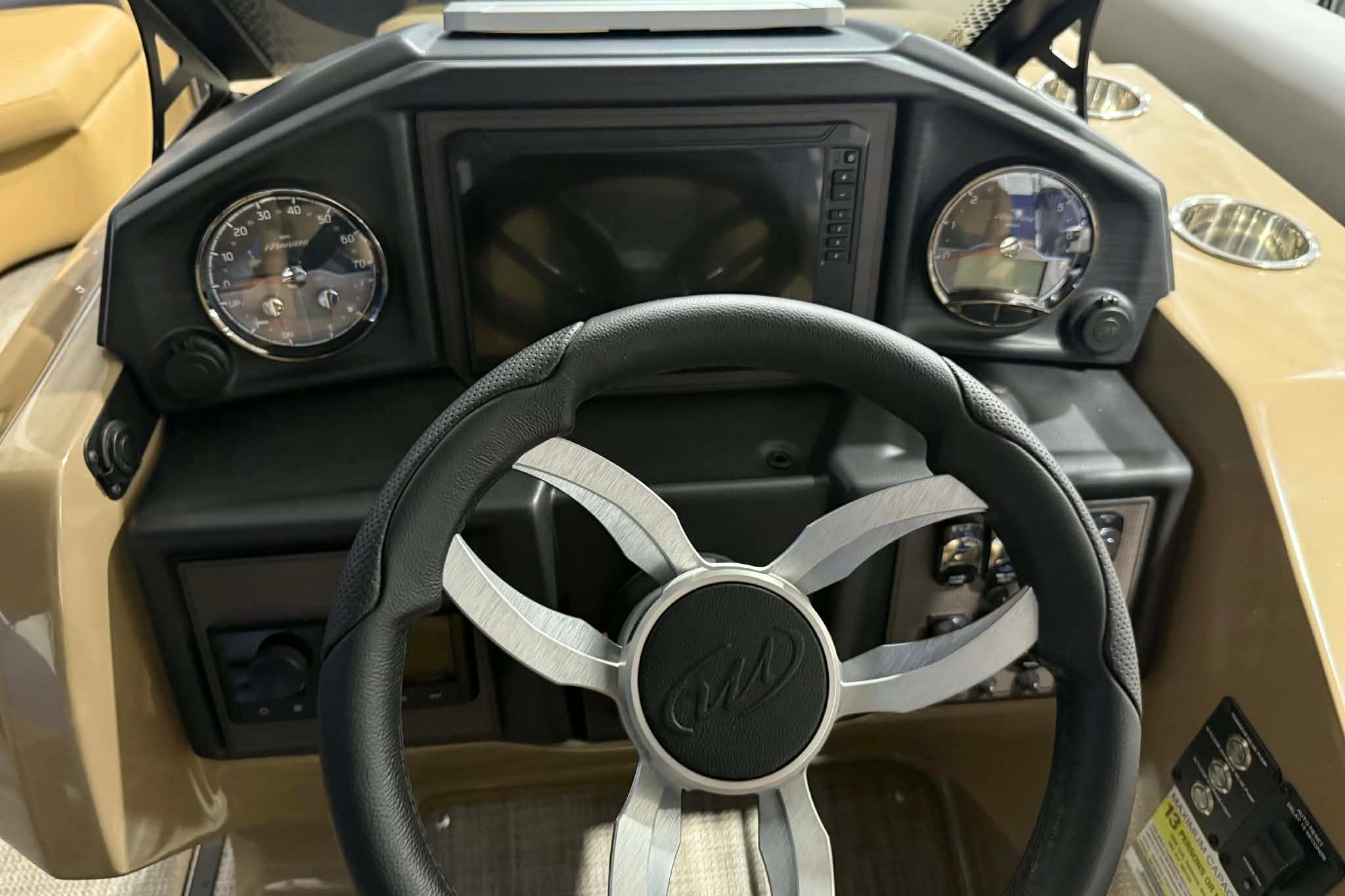 Steering console of 2026 Manitou Encore VP 230 pontoon boat, featuring modern gauges and controls.