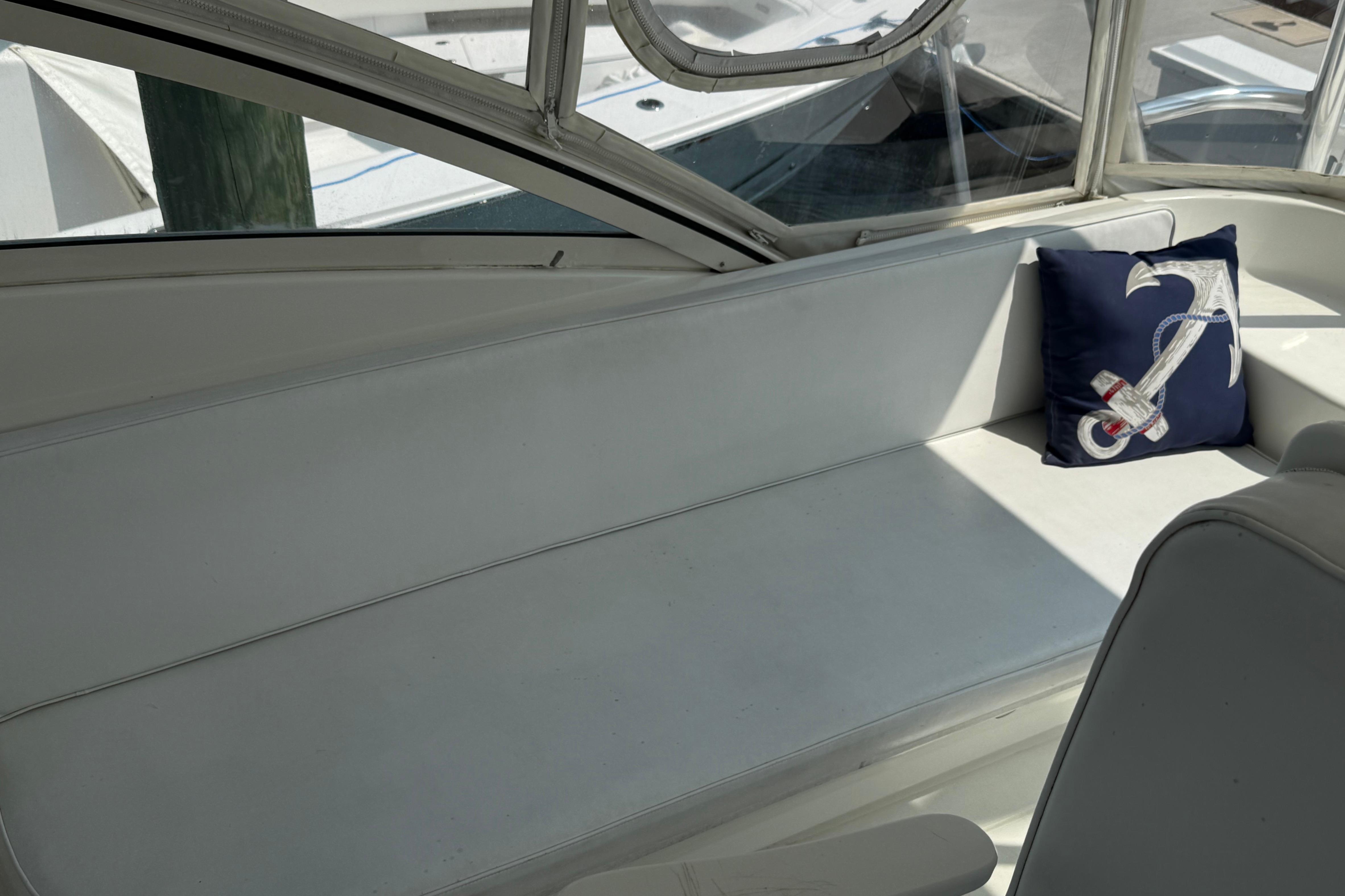 1999 Ocean Yachts 40 Express interior with white seating and anchor-themed pillow.
