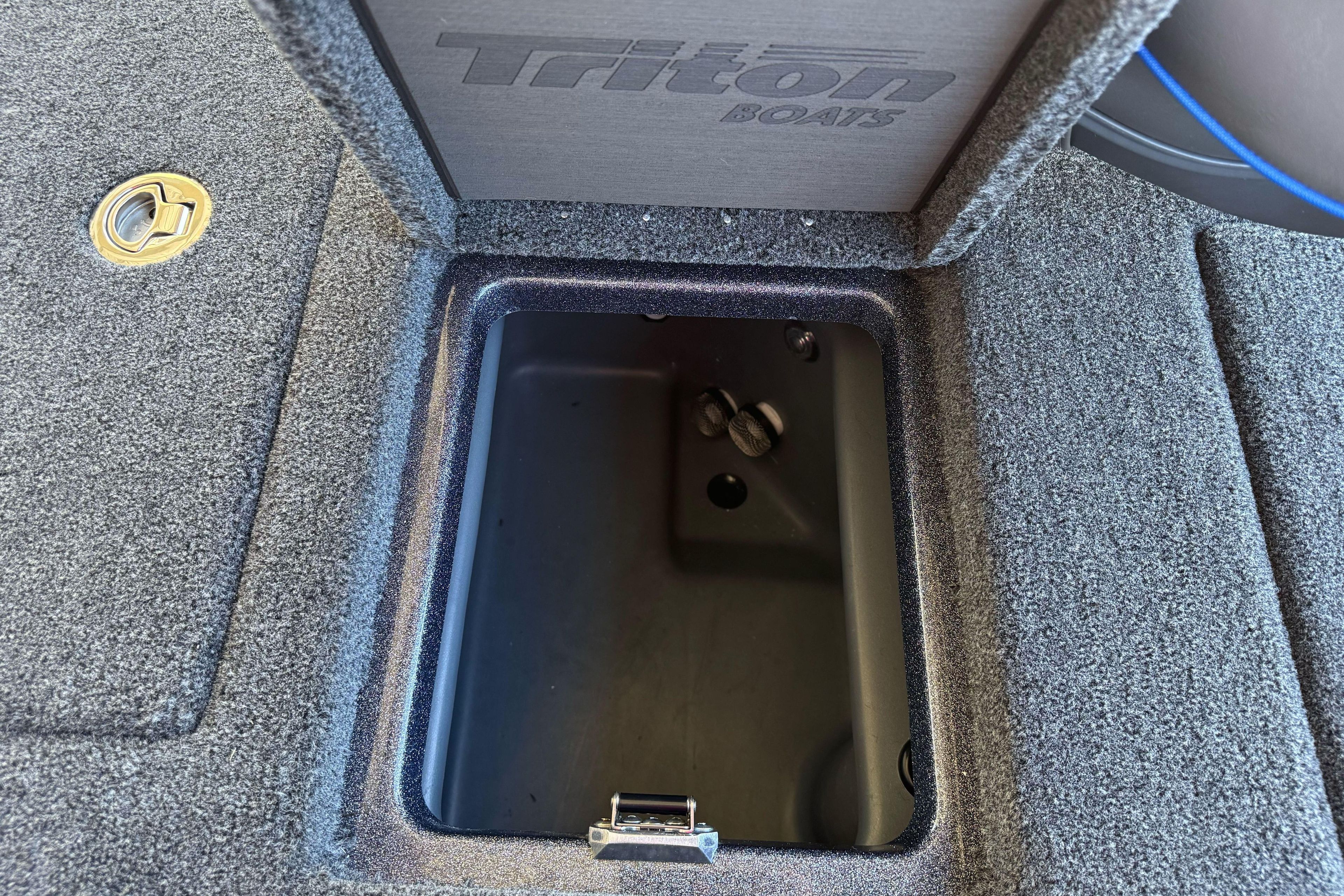 Open storage compartment on 2026 Triton 21XP Patriot boat, featuring carpeted interior.