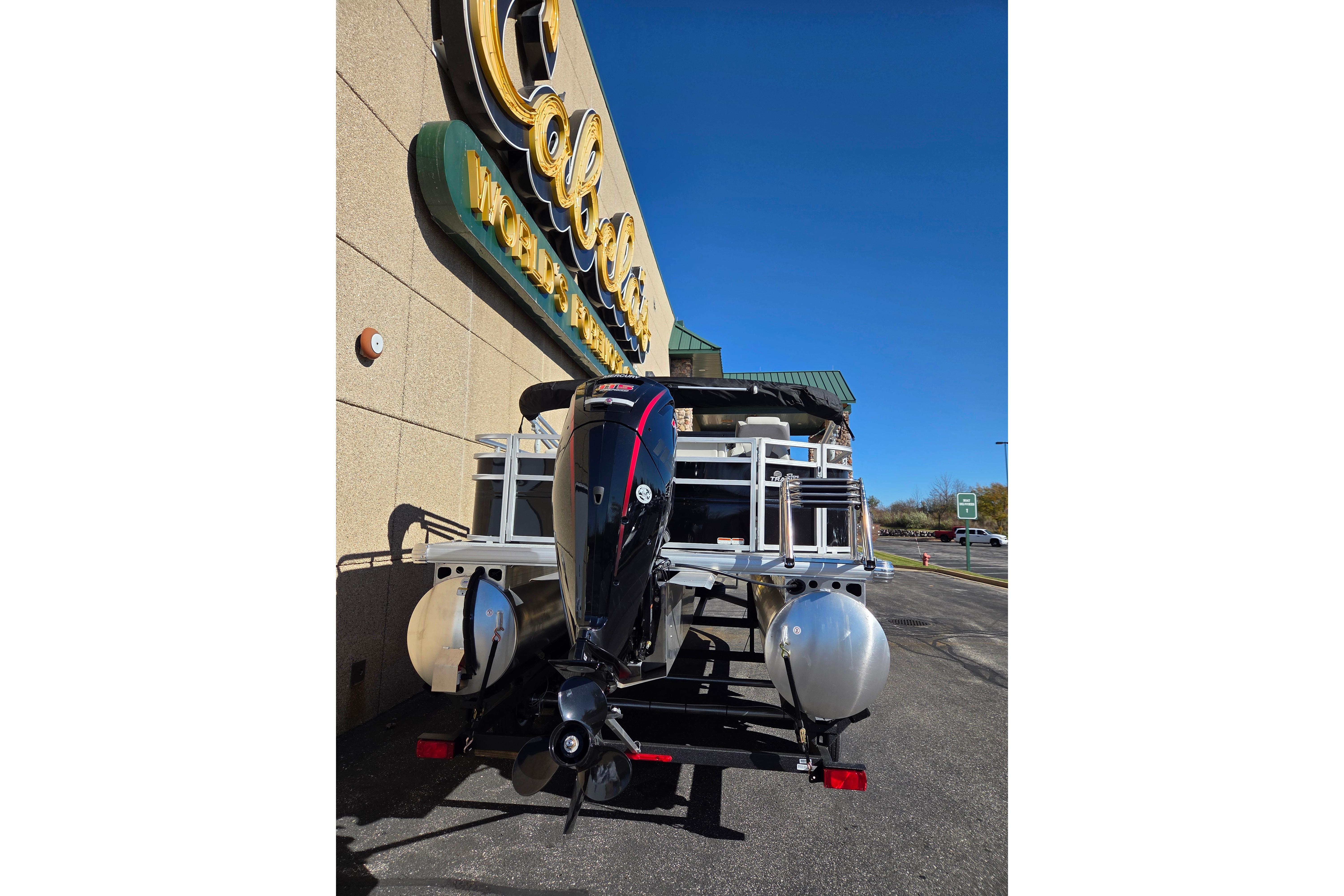 2026 Sun Tracker Fishin' Barge 20 DLX parked outside Cabela's store.