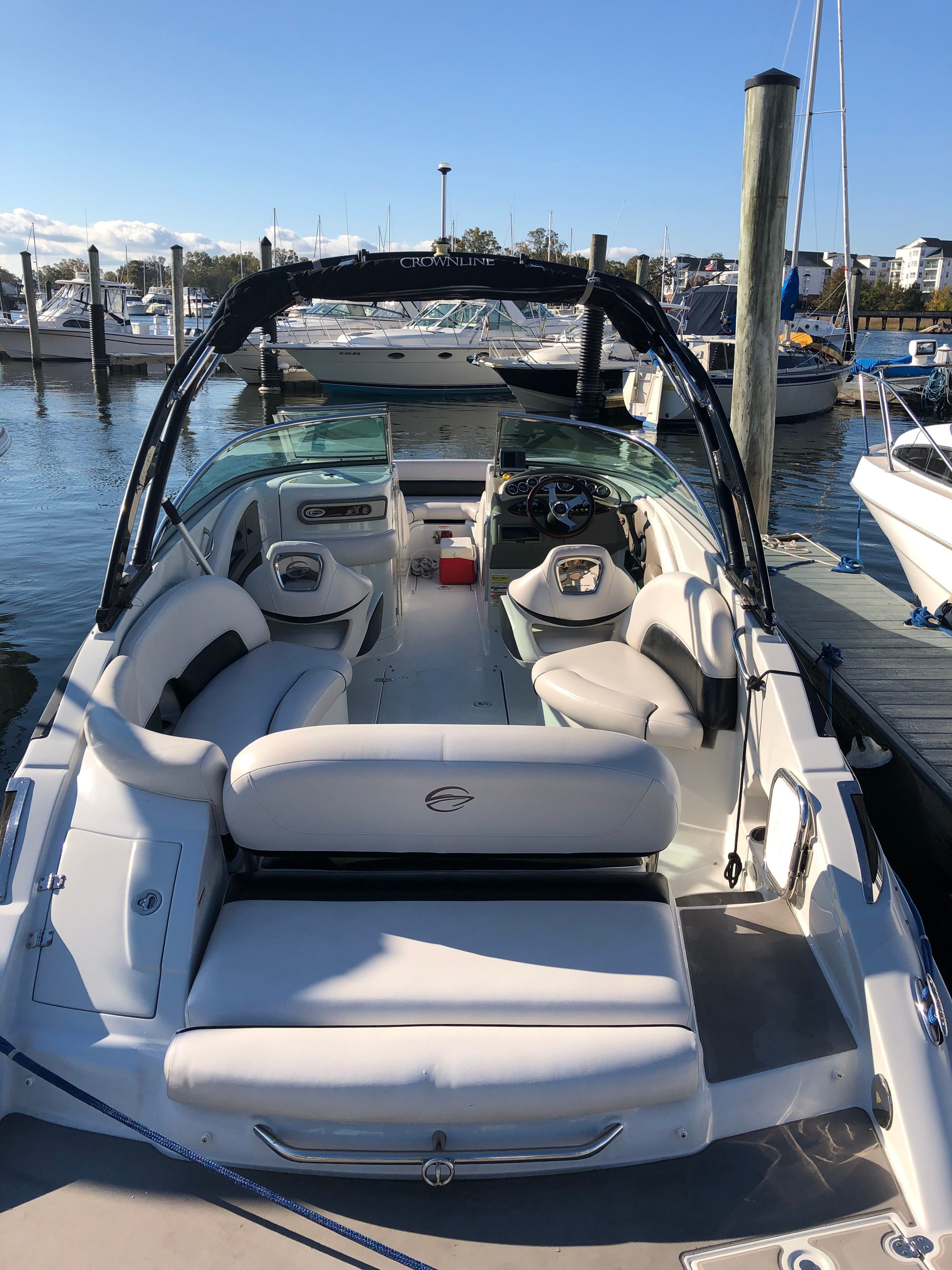 A 2013 Crownline E-4 Bowrider docked at a marina. It features white upholstery and an open deck.