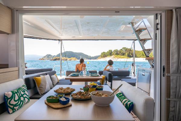 Luxurious Lagoon 43 yacht interior with dining setup, ocean view, and people relaxing, 2025 model.