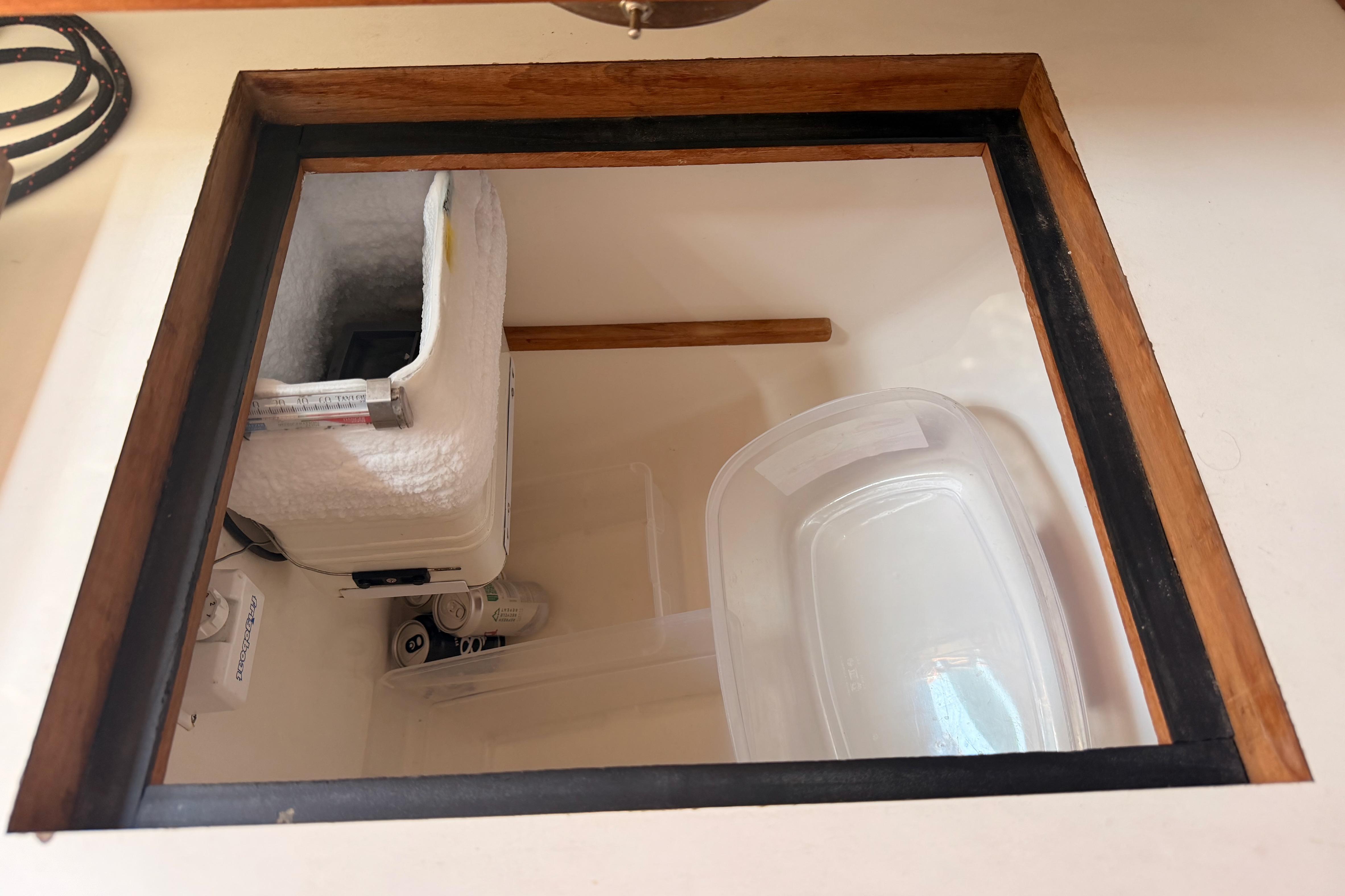 Storage compartment in a 1991 Caliber 33 boat, featuring insulated container and plastic bin.