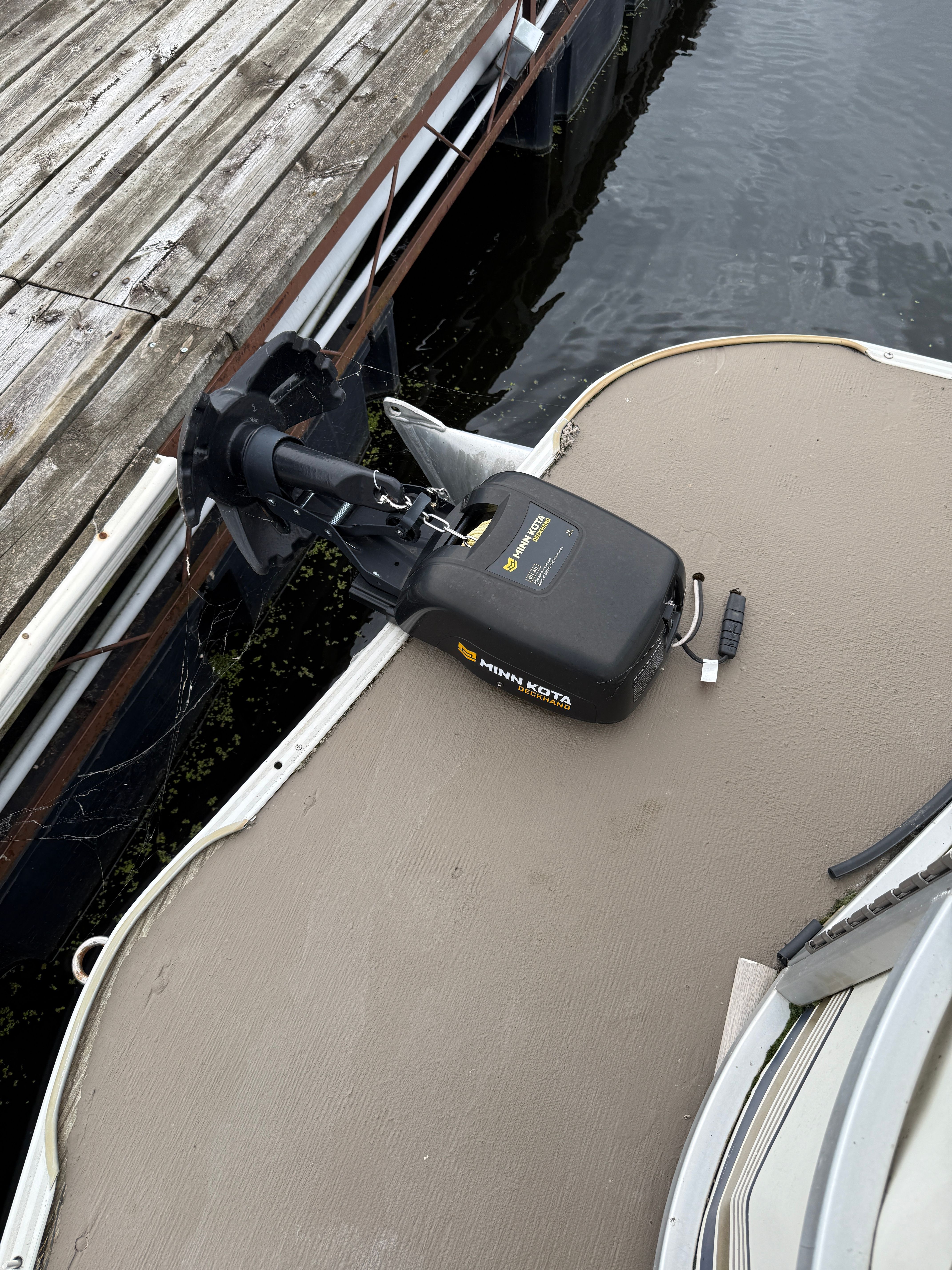 A boat with a Minn Kota motor at the stern, next to a wooden dock.