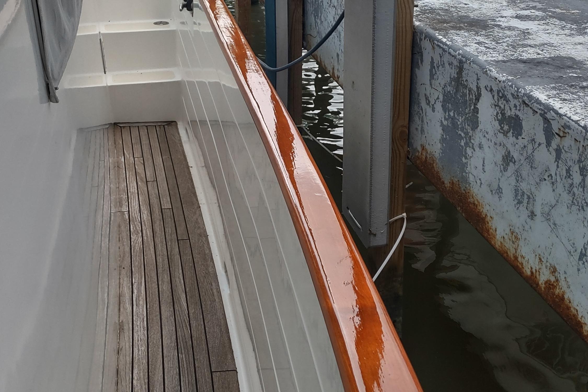 Kadey-Krogen 39 yacht deck with polished wood railing, docked beside a weathered pier.