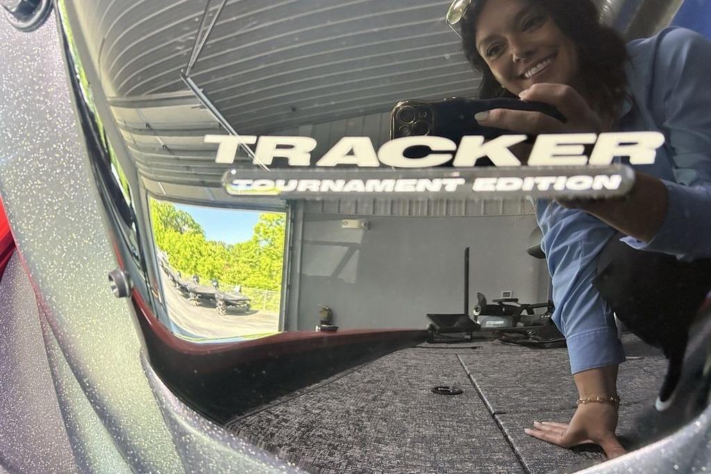 Reflection on Tracker Pro Team 195 boat, 2026 model, with smiling person.