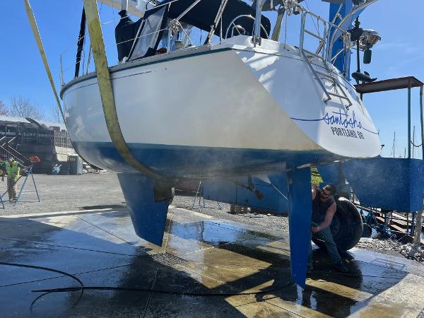 1984 Hunter 31 sailboat being cleaned at a marina, lifted by straps.