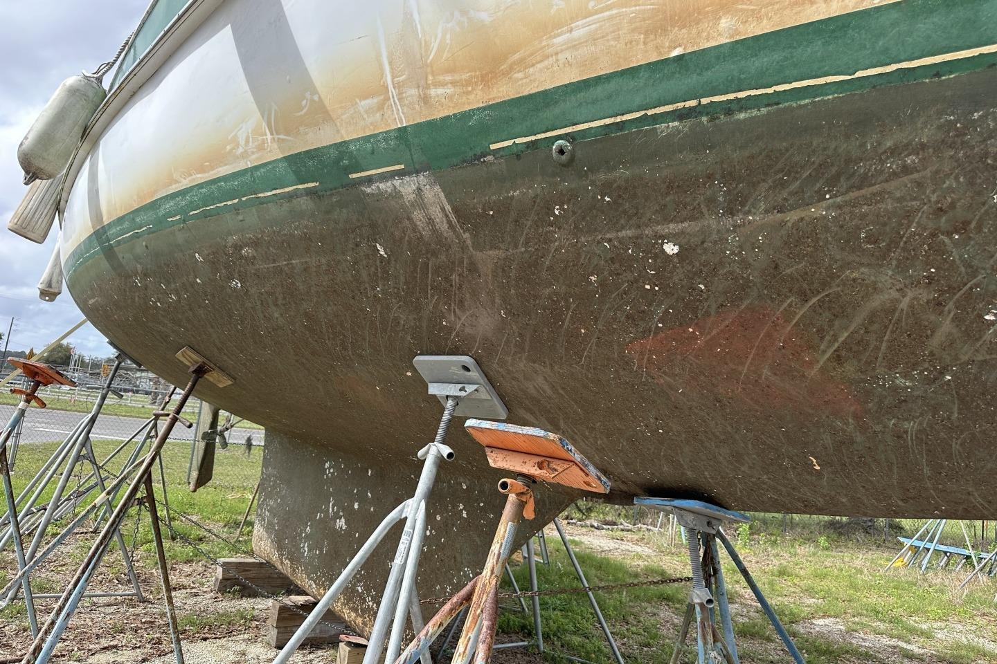 1976 Valiant 40 sailboat hull on stands, showing weathered condition and marine growth.