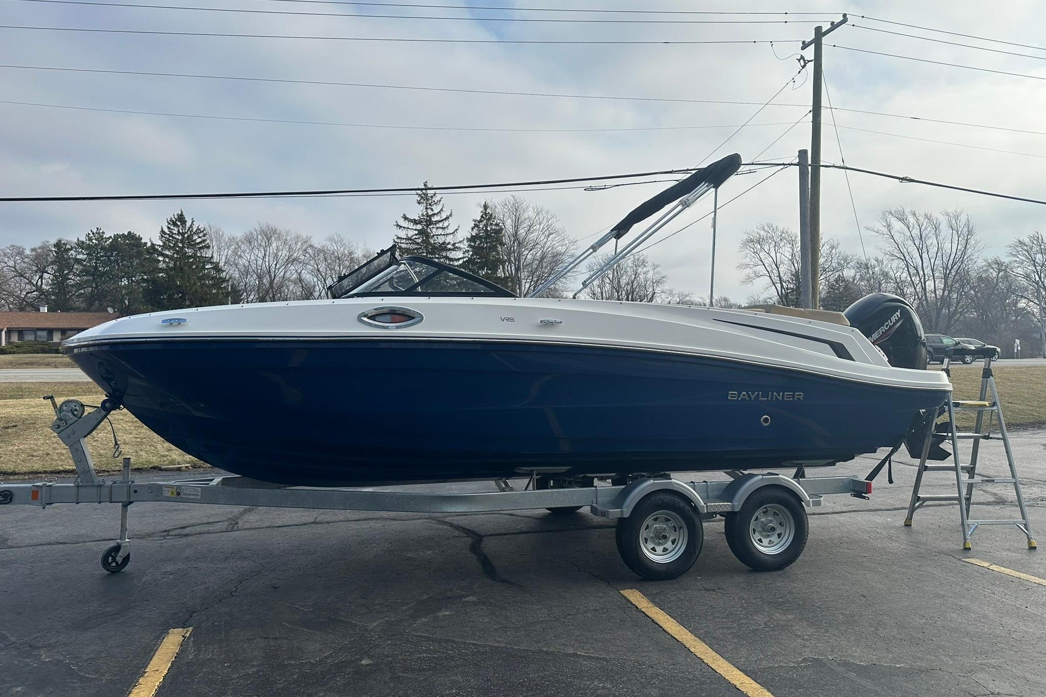 2026 Bayliner VR6 Bowrider OB on trailer, parked outdoors, side view.