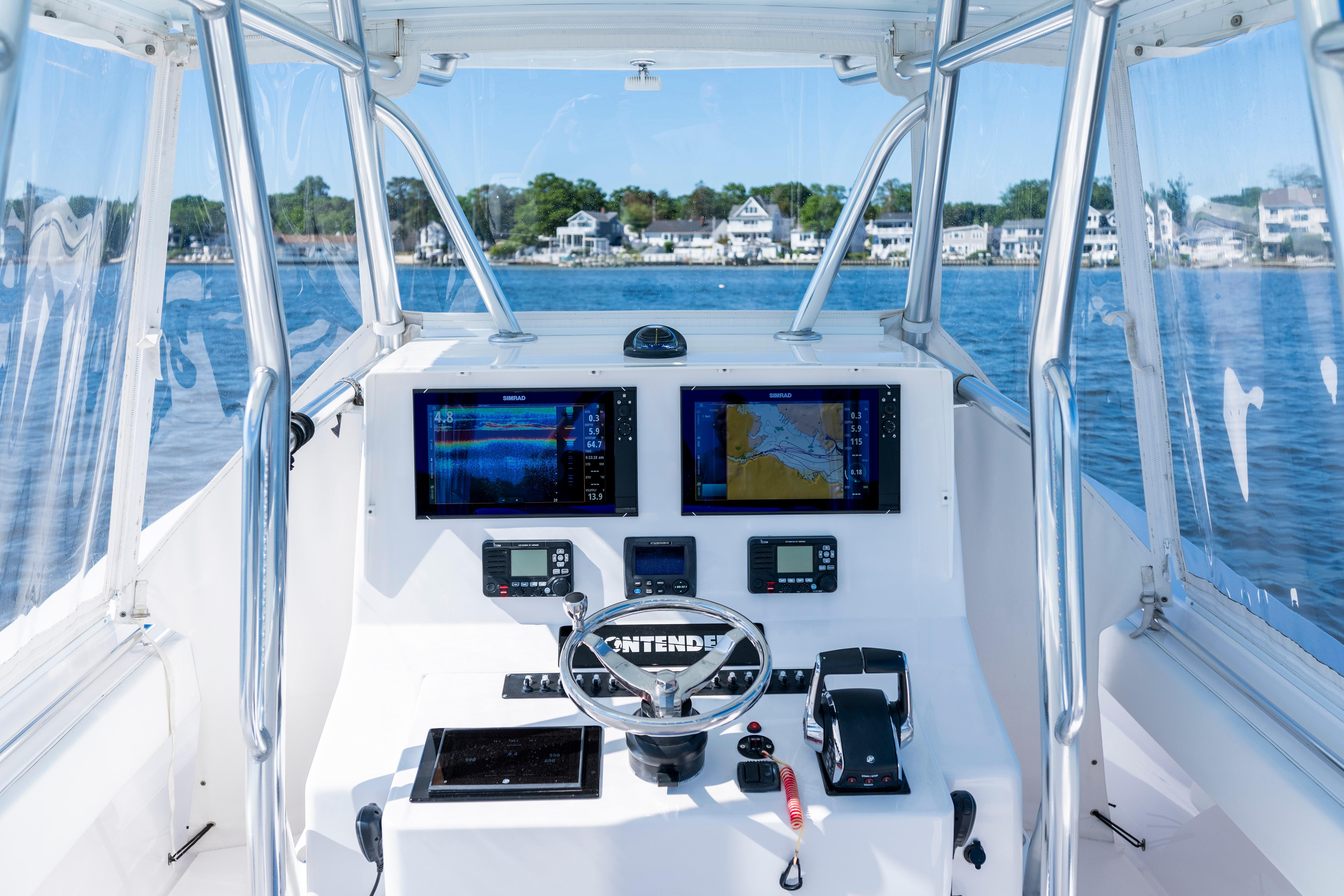 Cockpit view of 2015 Contender 39 ST boat with navigation screens and steering wheel.