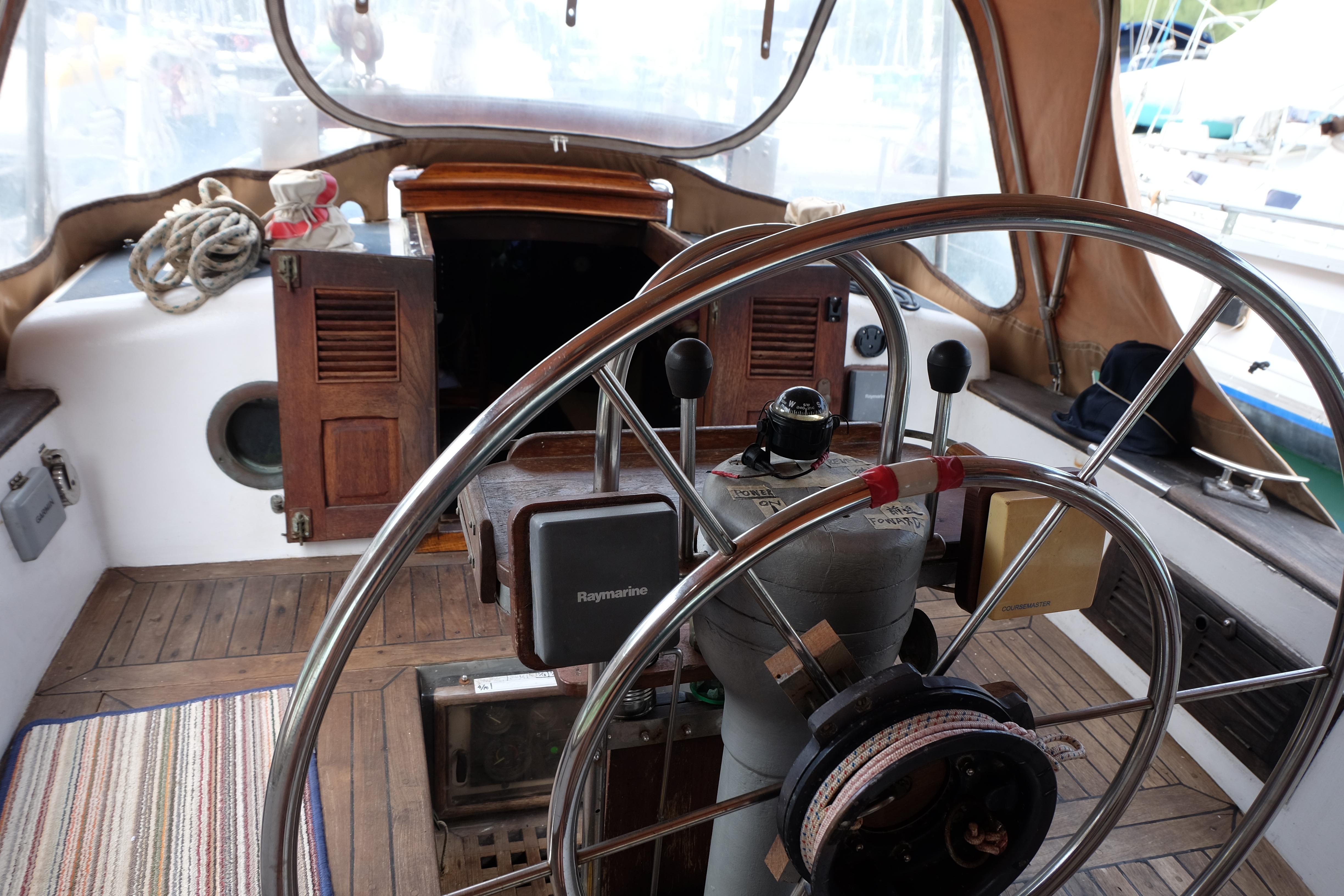 Cockpit of 1979 Westwind 35 sailboat with steering wheel and nautical equipment.