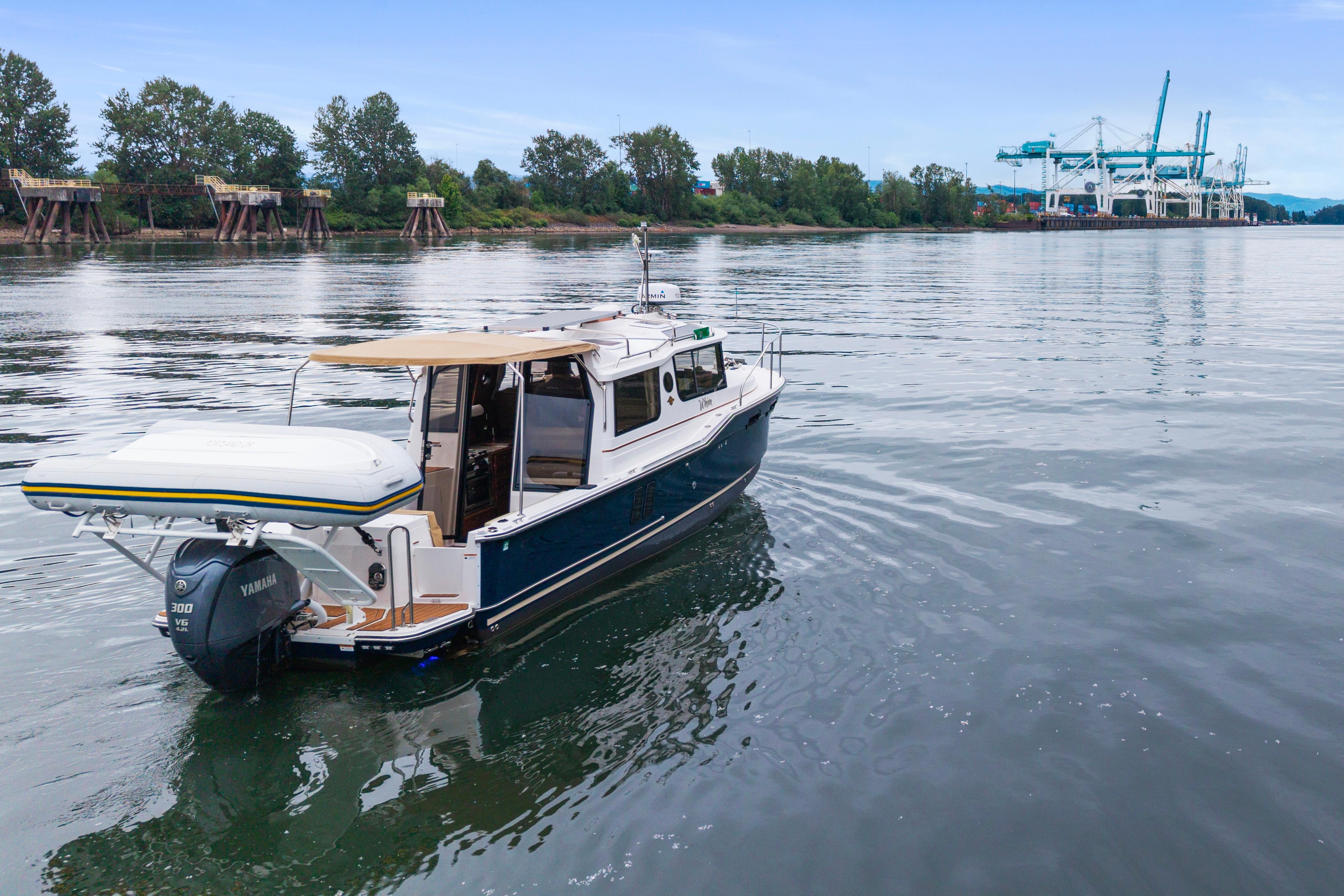 2022 Ranger Tugs R-27 boat on calm water near industrial docks.