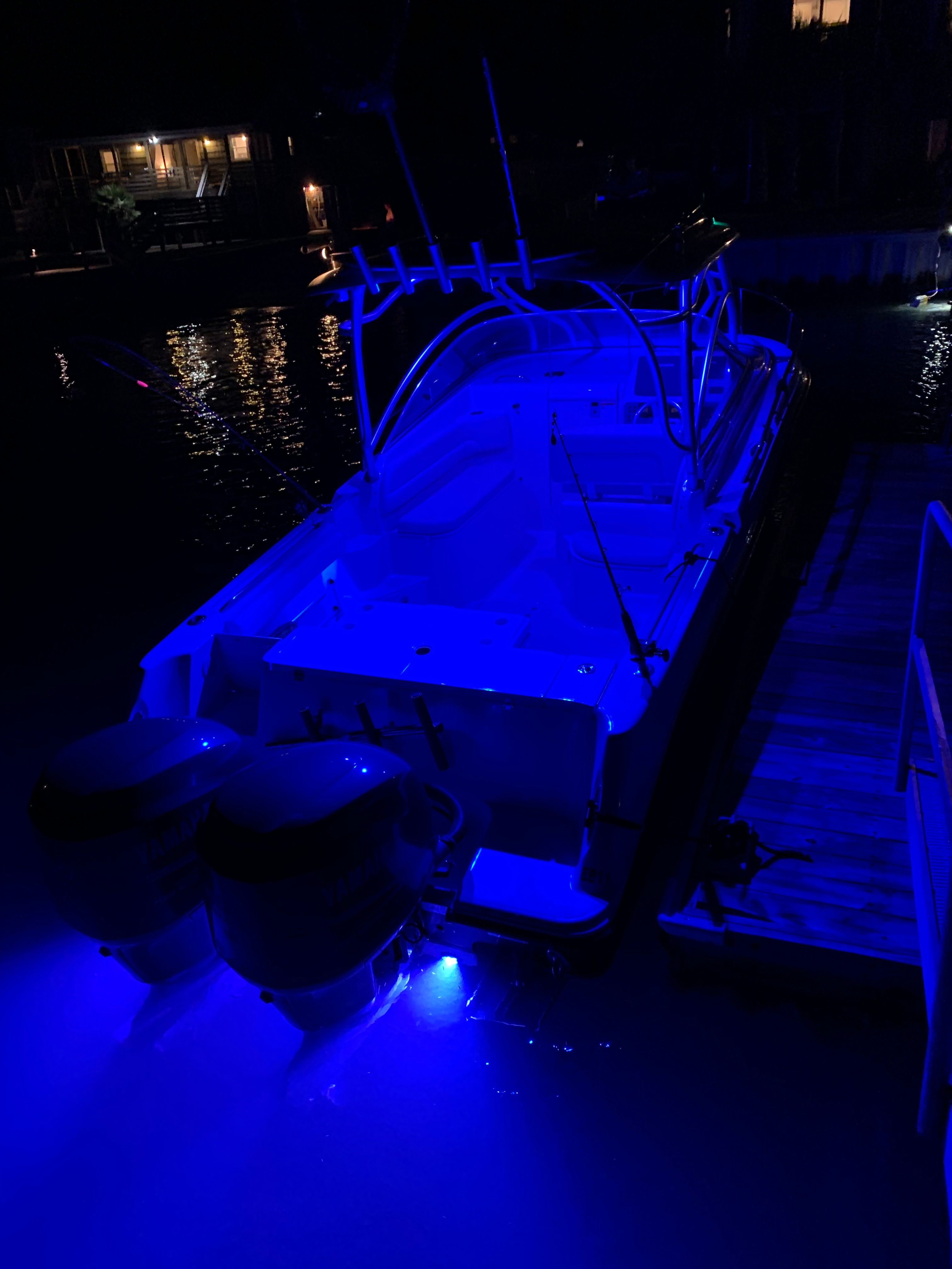 A lit-up boat docked at night, featuring two outboard motors.