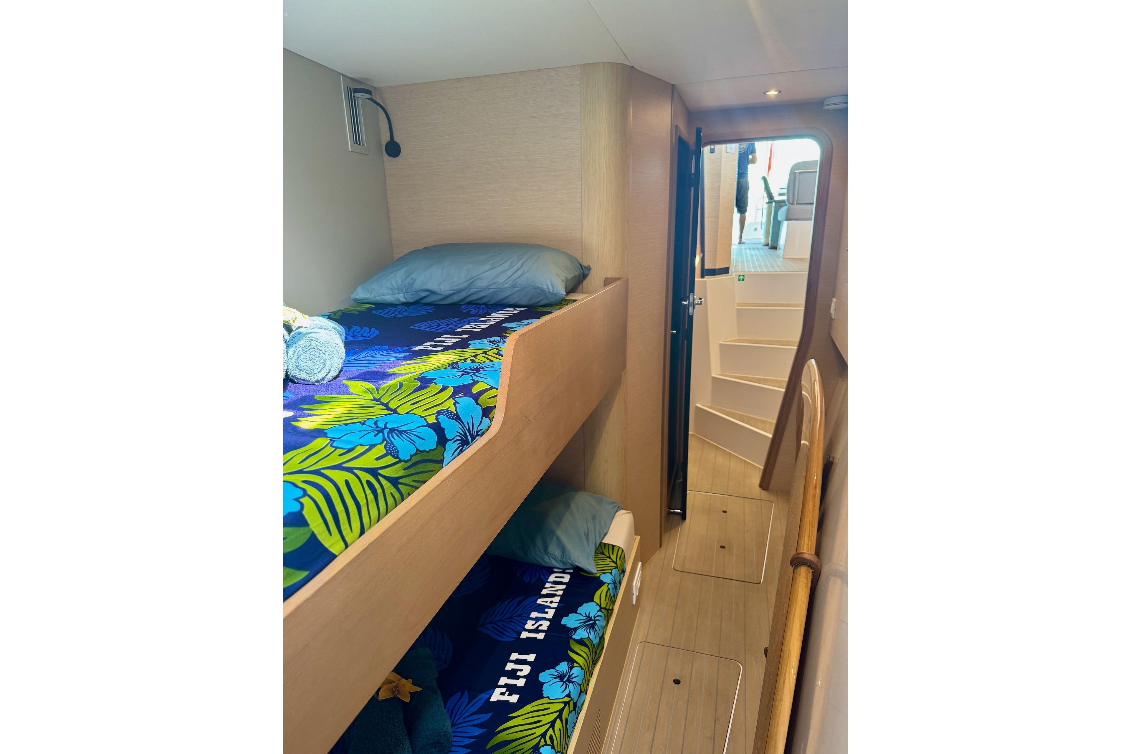 Interior of 2023 NEEL 52 yacht with bunk beds and tropical-themed bedding.