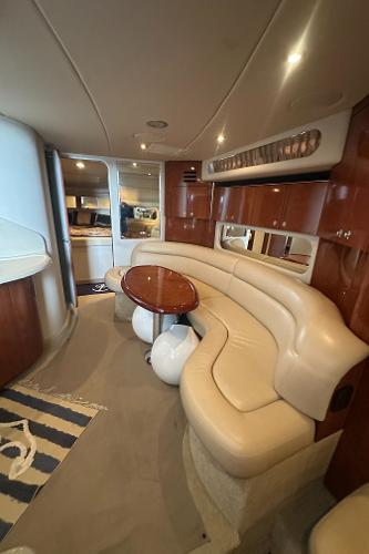 Luxurious interior of 2004 Sea Ray 380 Sundancer yacht with curved seating and wooden accents.