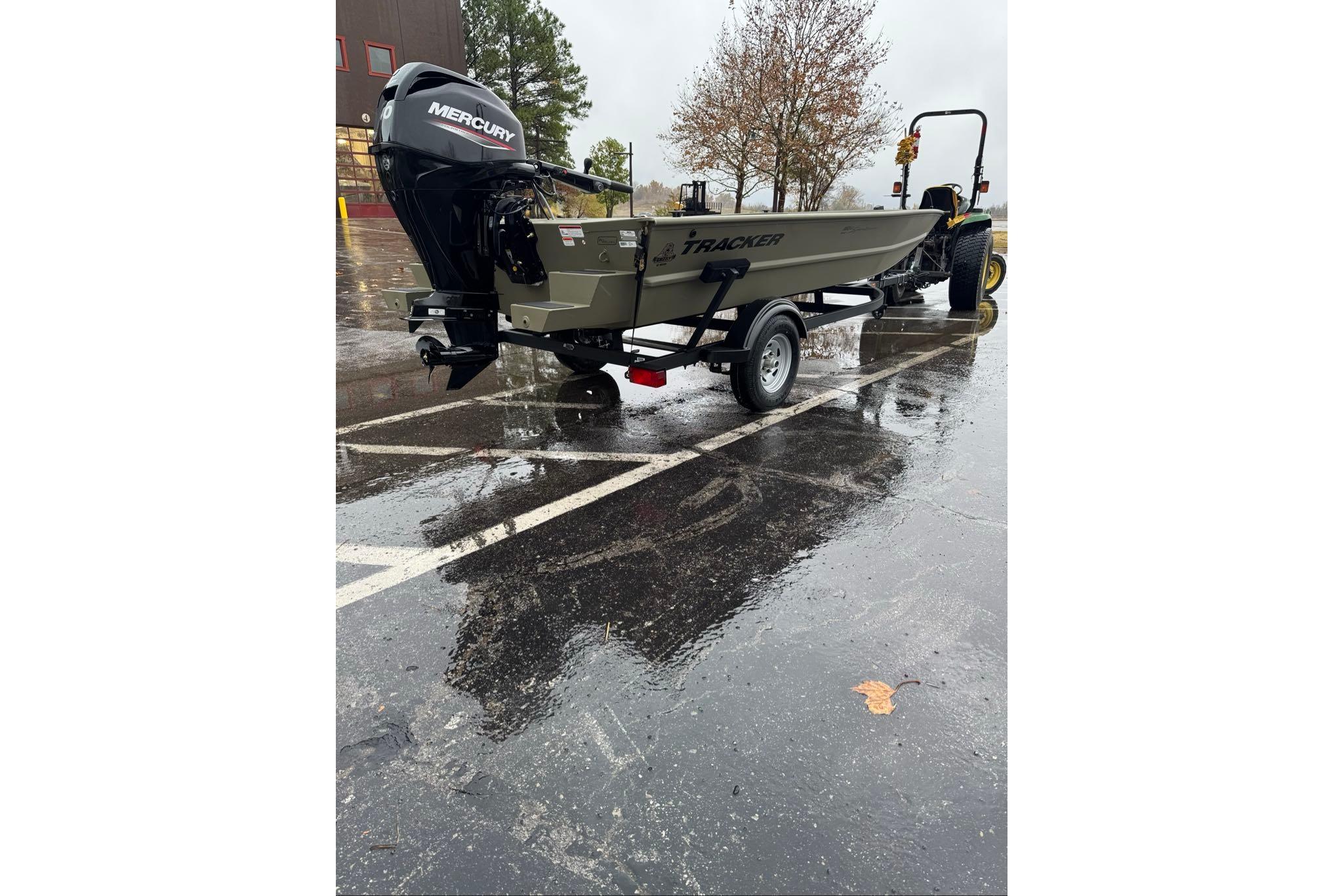 2026 Tracker Grizzly 1654 T Sportsman boat on trailer in rainy parking lot.