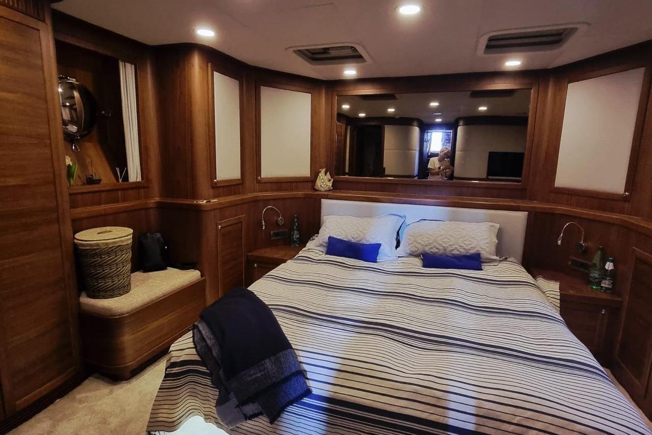 Luxurious cabin interior of 2018 Bering 65 yacht with cozy bed and wooden decor.