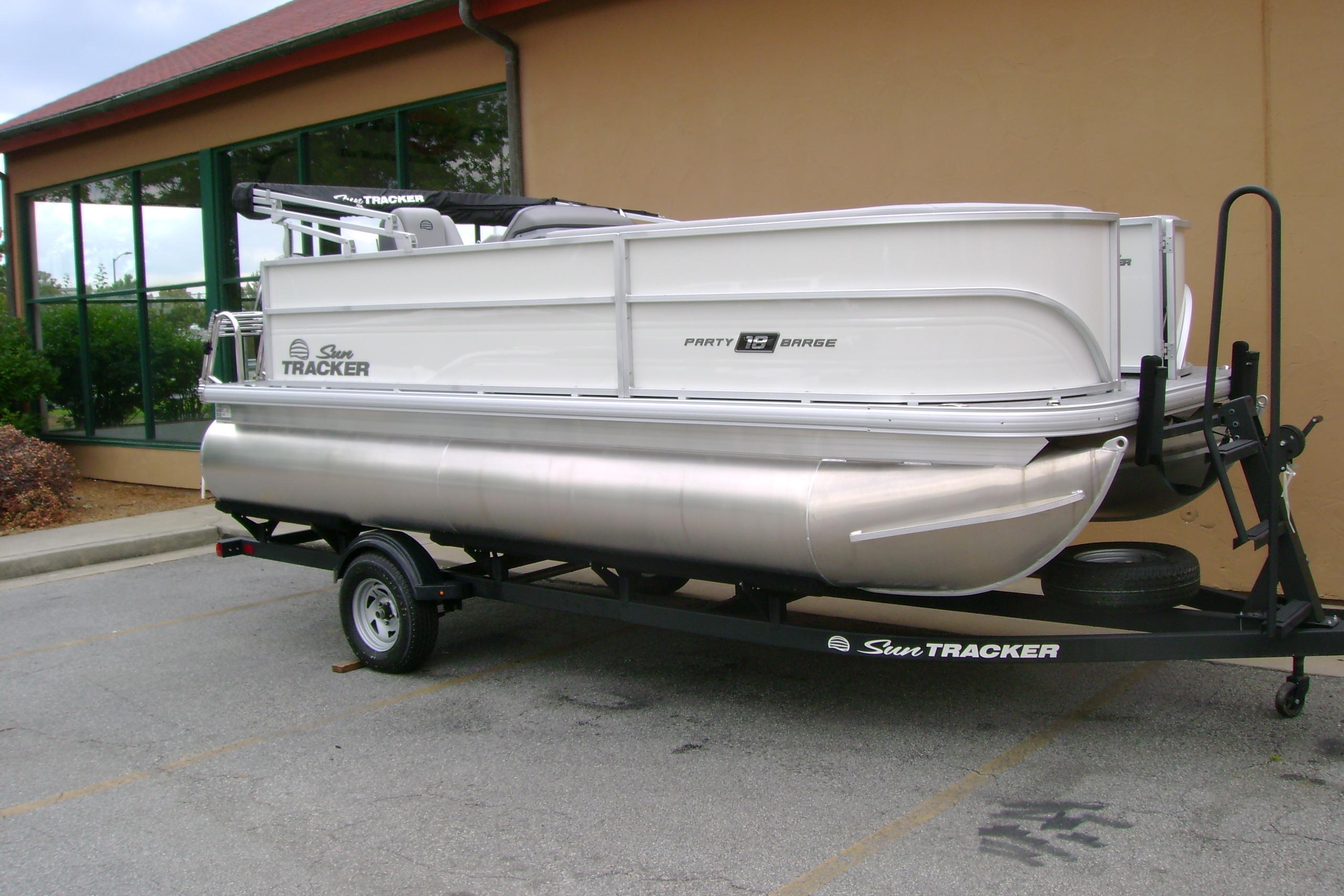 2026 Sun Tracker Party Barge 18 DLX pontoon boat on trailer, parked outdoors.