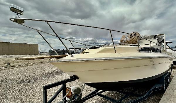 1987 Sea Ray 270 Sundancer boat on trailer under cloudy sky.