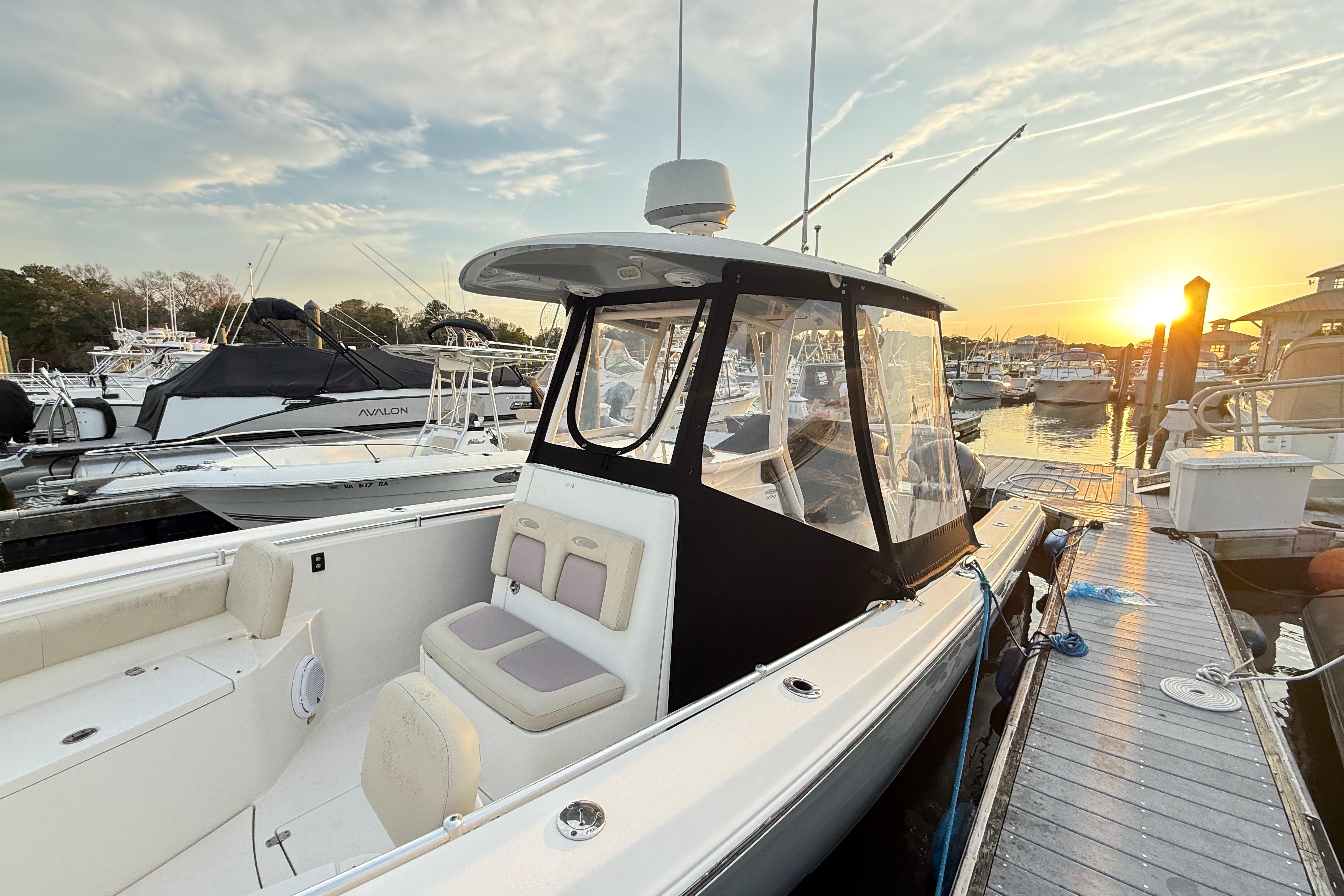 2016 Cobia 296 Center Console boat docked at sunset, featuring sleek design and spacious seating.