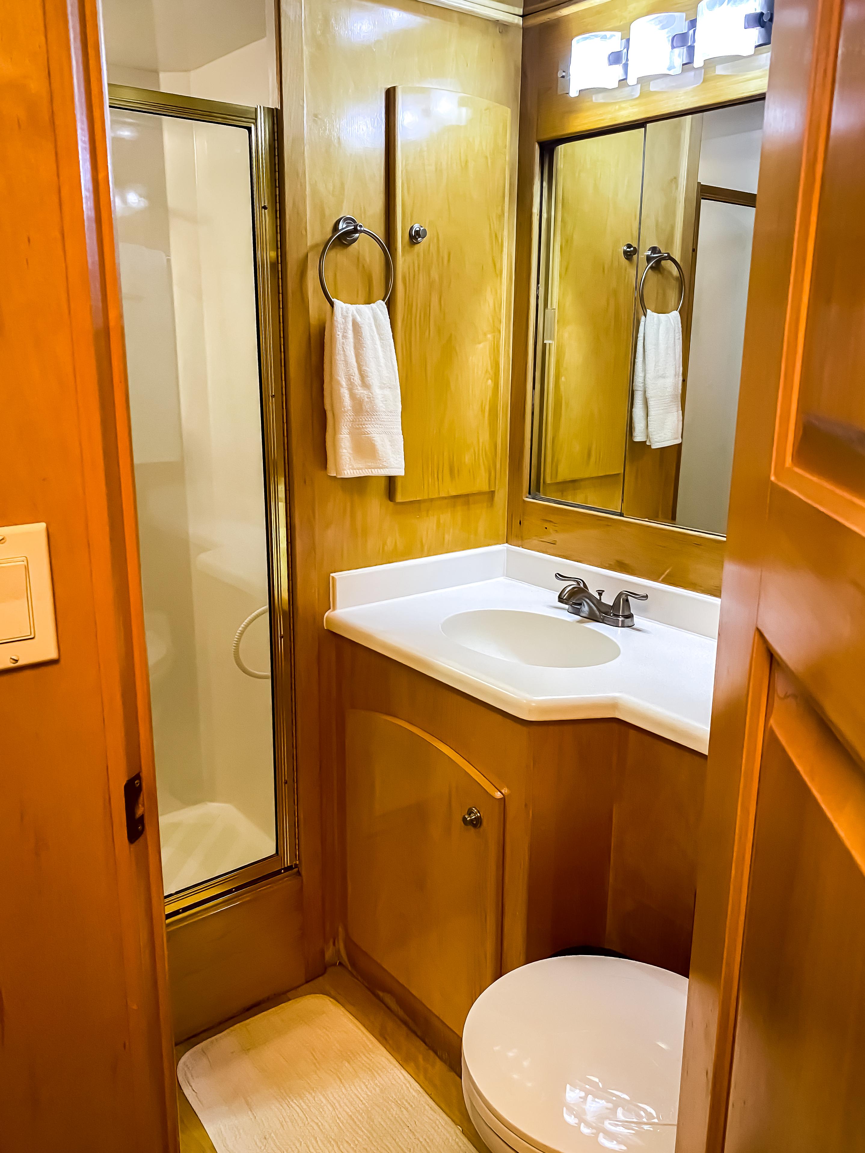 1999 Navigator 5800 yacht bathroom with wood cabinetry, shower, and vanity.