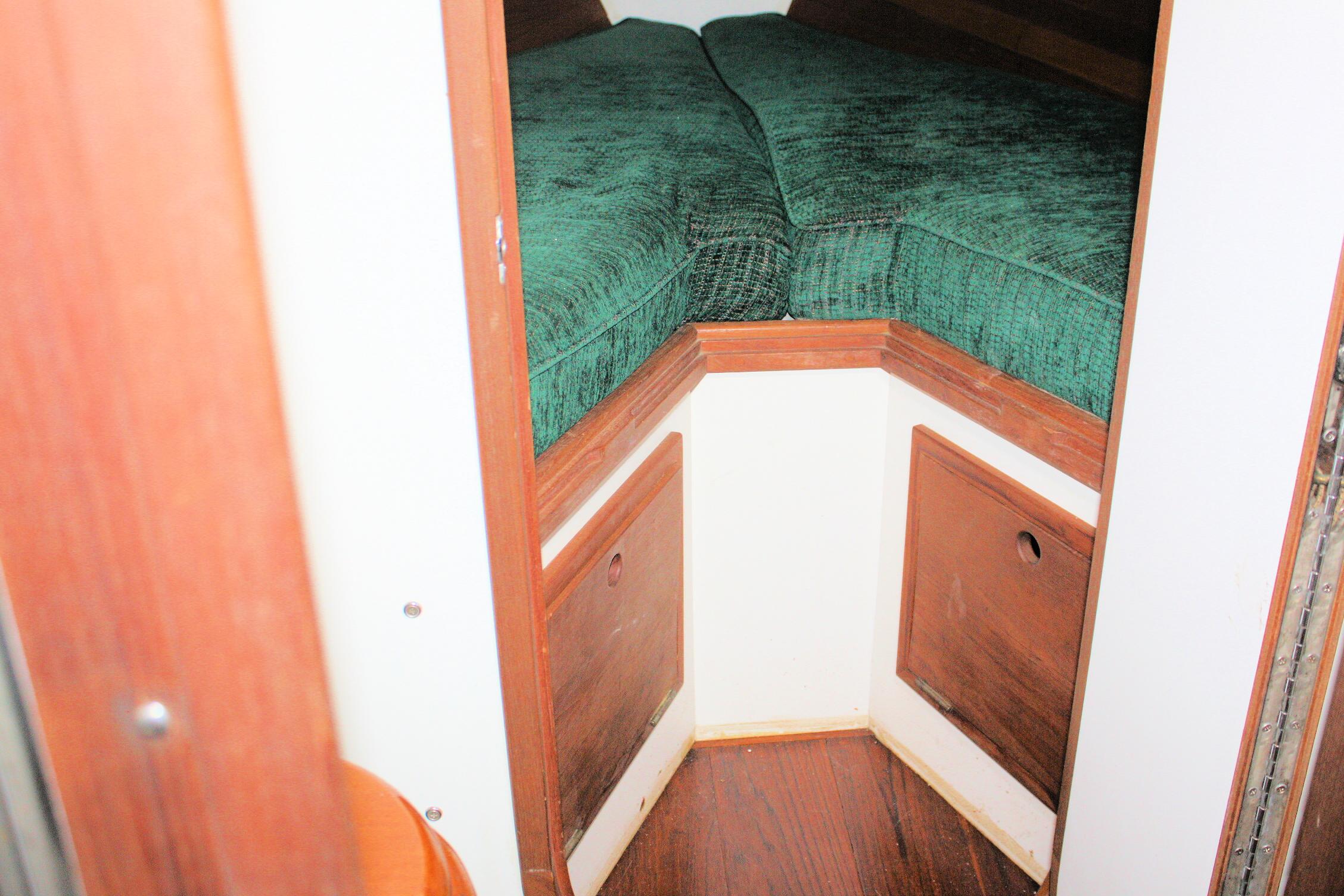 Cozy cabin interior of 1987 Morris Linda boat with green cushions and wooden accents.