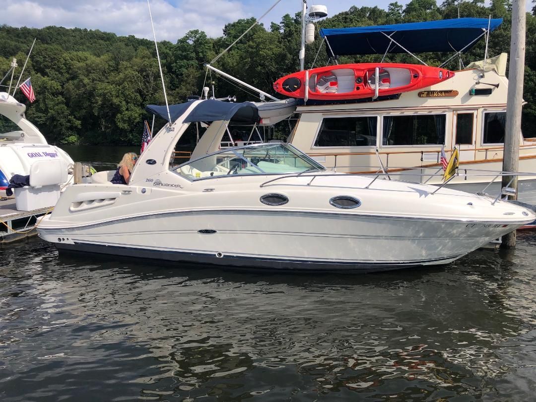 A white 2005 Sea Ray Sundancer 260 boat docked, featuring a blue canopy.