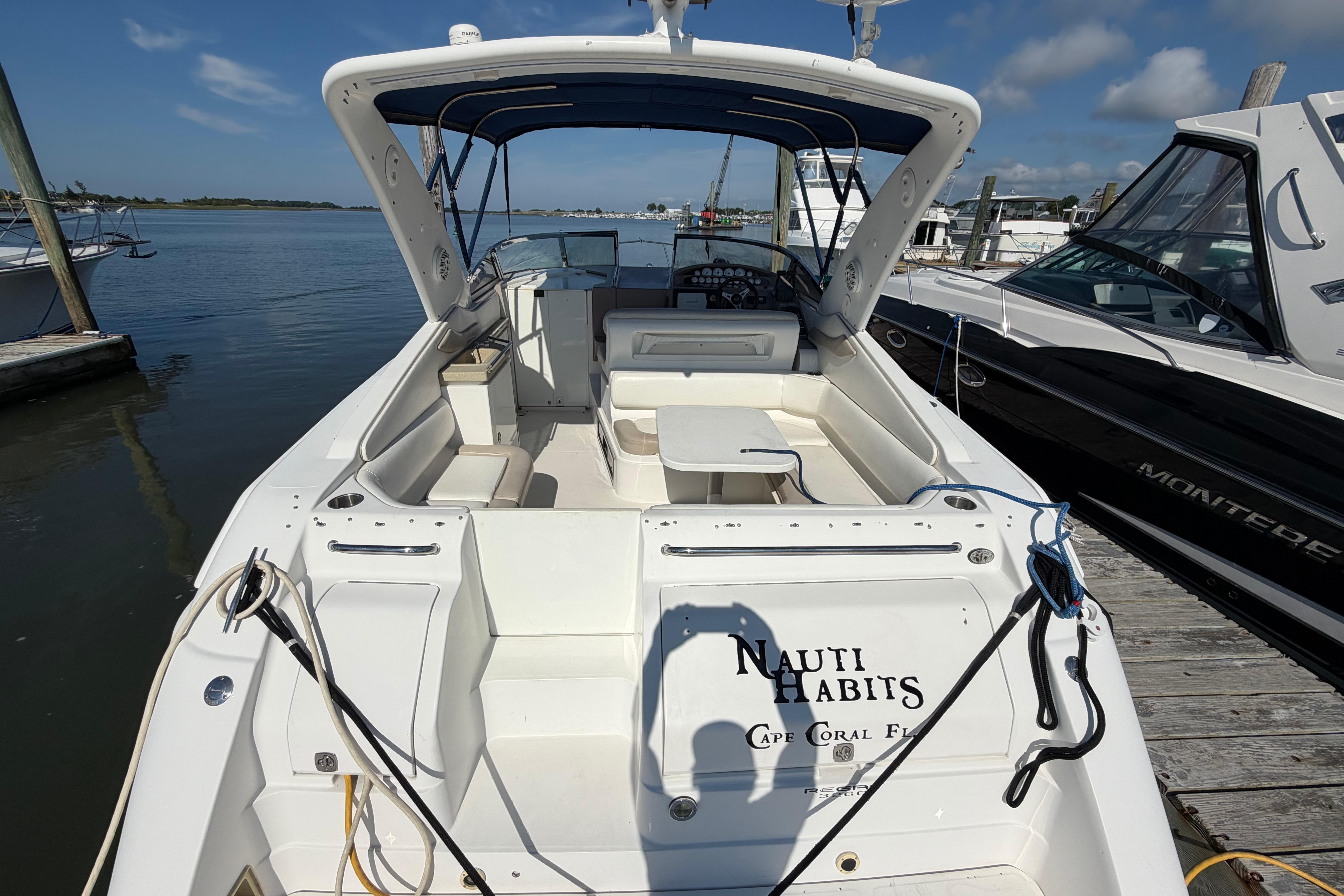 2003 Regal Commodore 3260 boat docked, featuring spacious seating and "Nauti Habits" name.