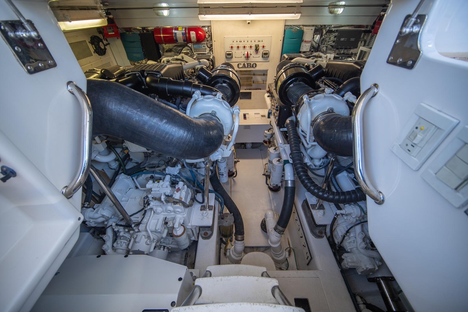 Engine room of 2009 Cabo 52 Flybridge yacht, showcasing dual engines and control panel.