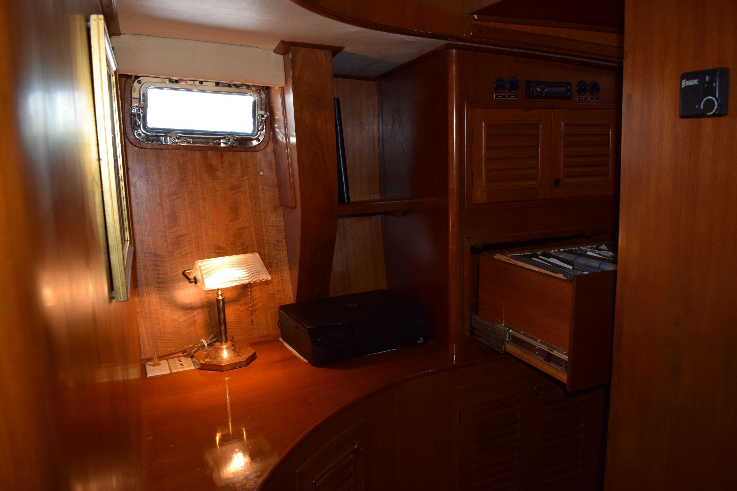 Interior of 1980 Cheoy Lee 52 Motorsailer with wooden cabinetry and desk lamp.