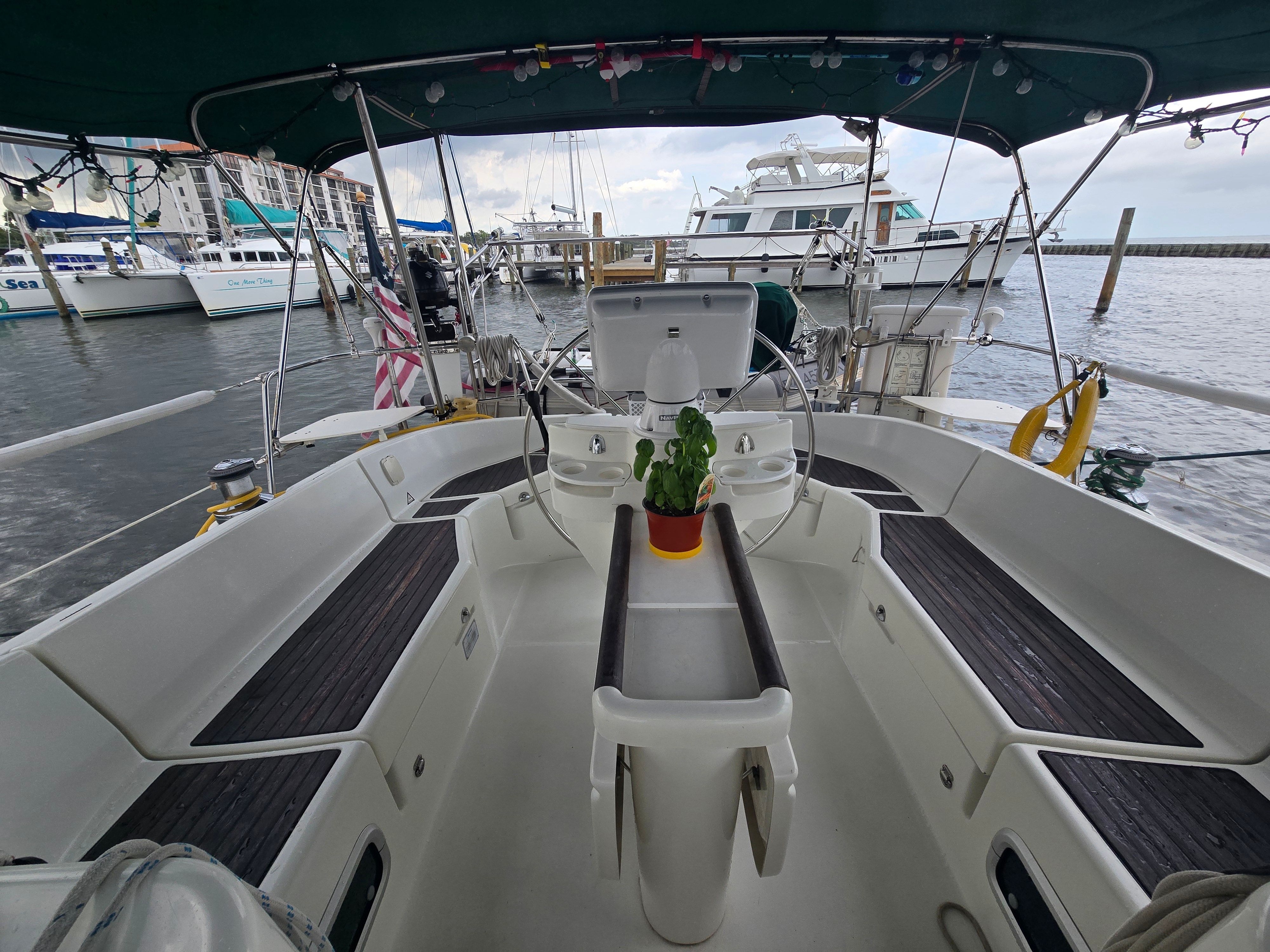 The cockpit of a 1998 Beneteau 411 with a table and plant in the center.